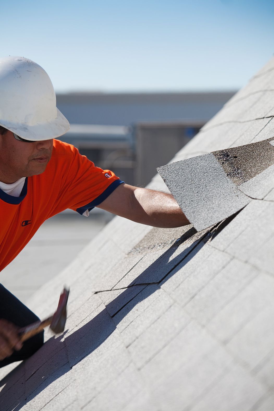 A man wearing a hard hat is working on a roof