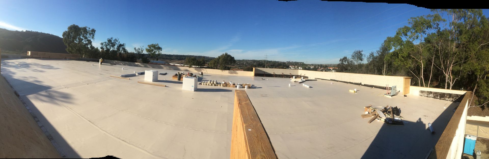 A panoramic view of a white roof with trees in the background.