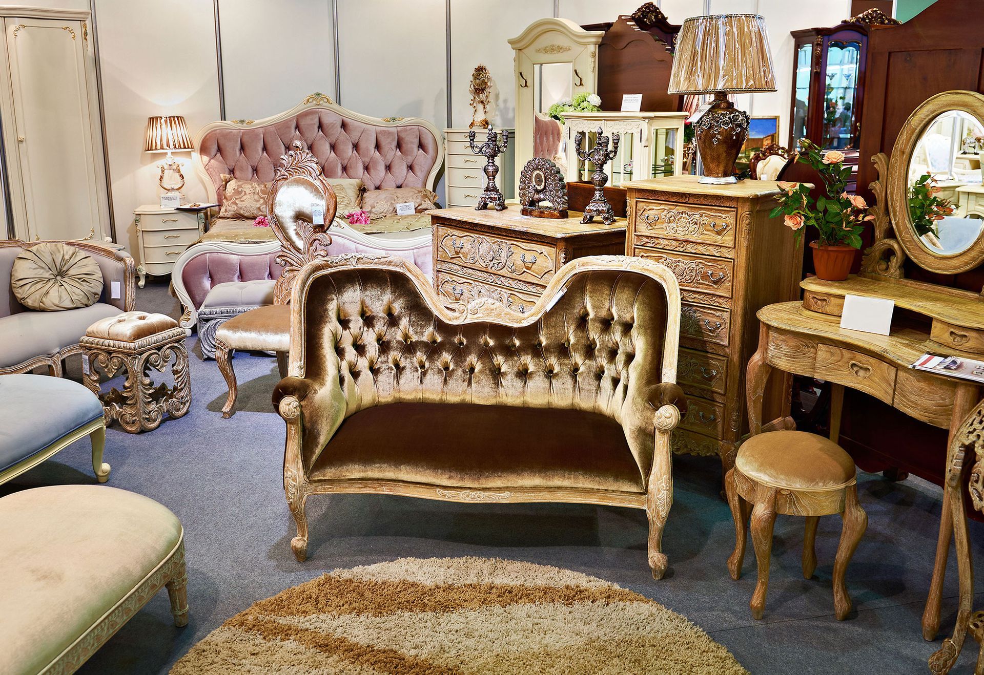 Display of ornate antique furniture, including sofas, a bed, a vanity, and decorative items.