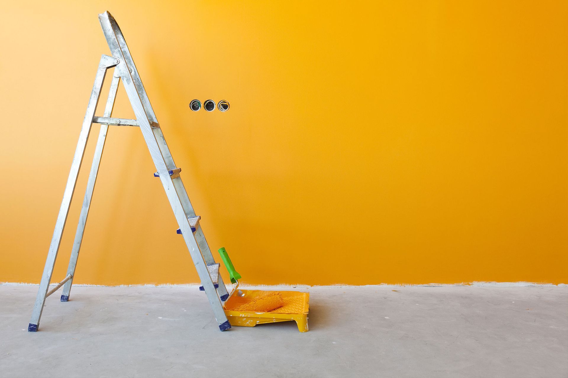 A ladder is sitting in front of a yellow wall.