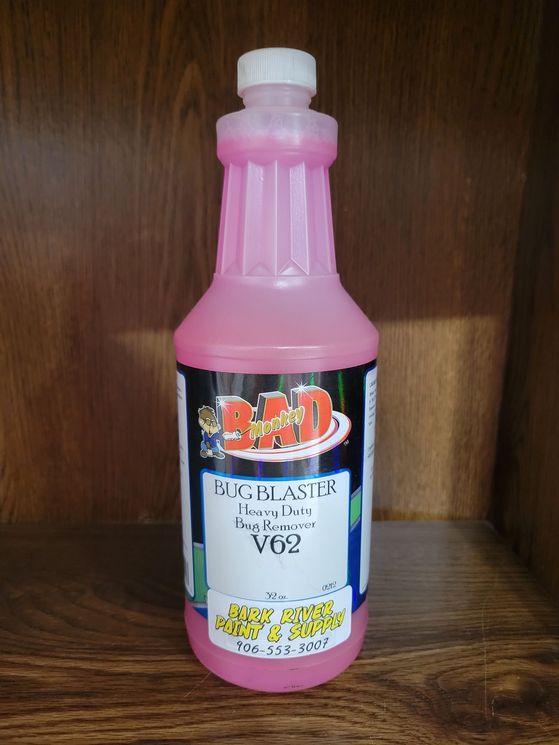 Pink bottled beverage with a white cap and label, standing on a wooden shelf.