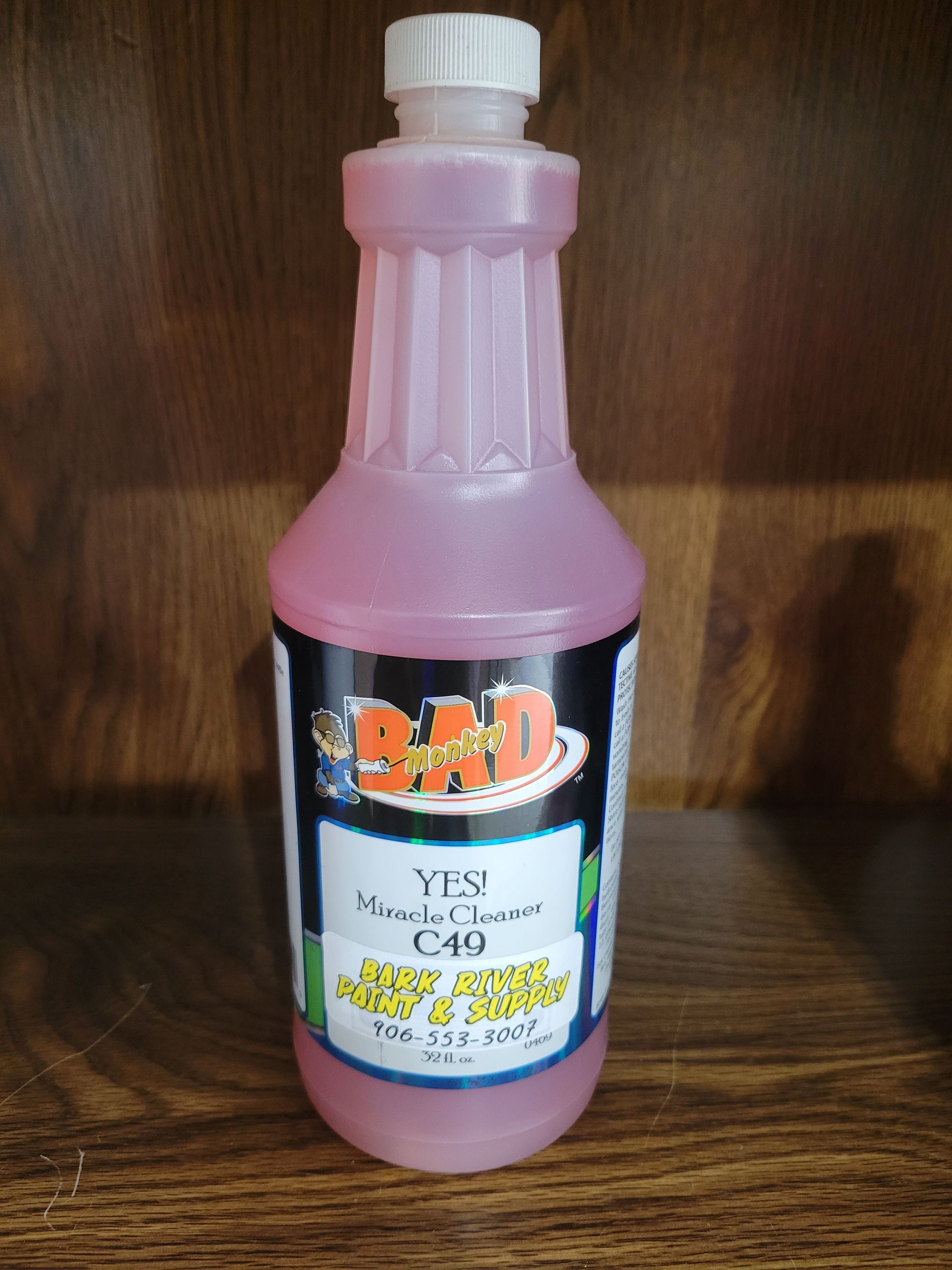 Pink bottle with a white cap and black label standing on a wooden surface