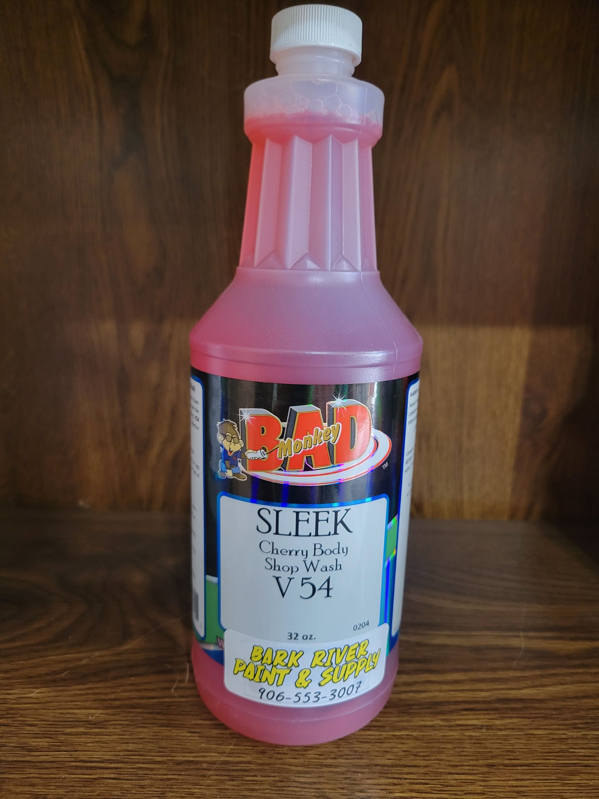 Pink cleaning solution bottle with white cap and label on a wooden surface.