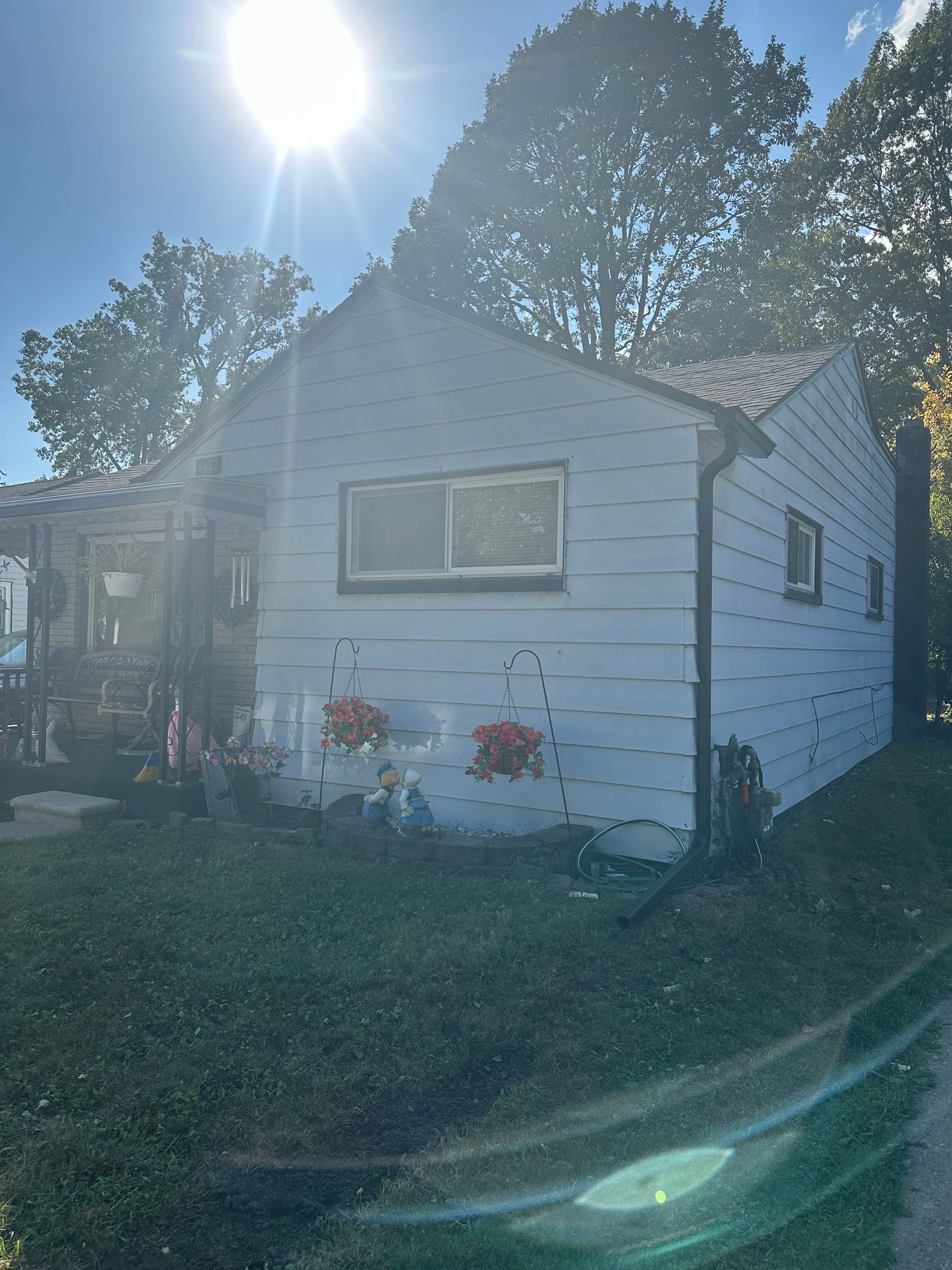 A small, light-blue house with a lawn. Bright sunlight shines in the background.