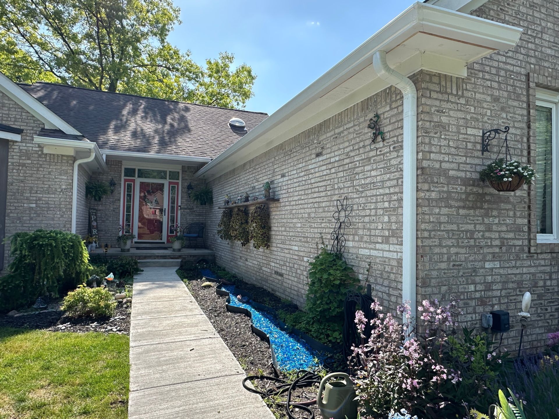 Exterior view of a brick house with a white trim, gutters, and a walkway leading to the front door.