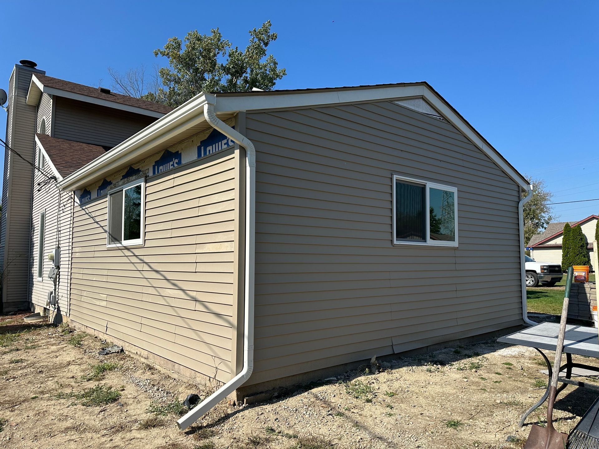 New house addition with tan siding, white trim, and a window.