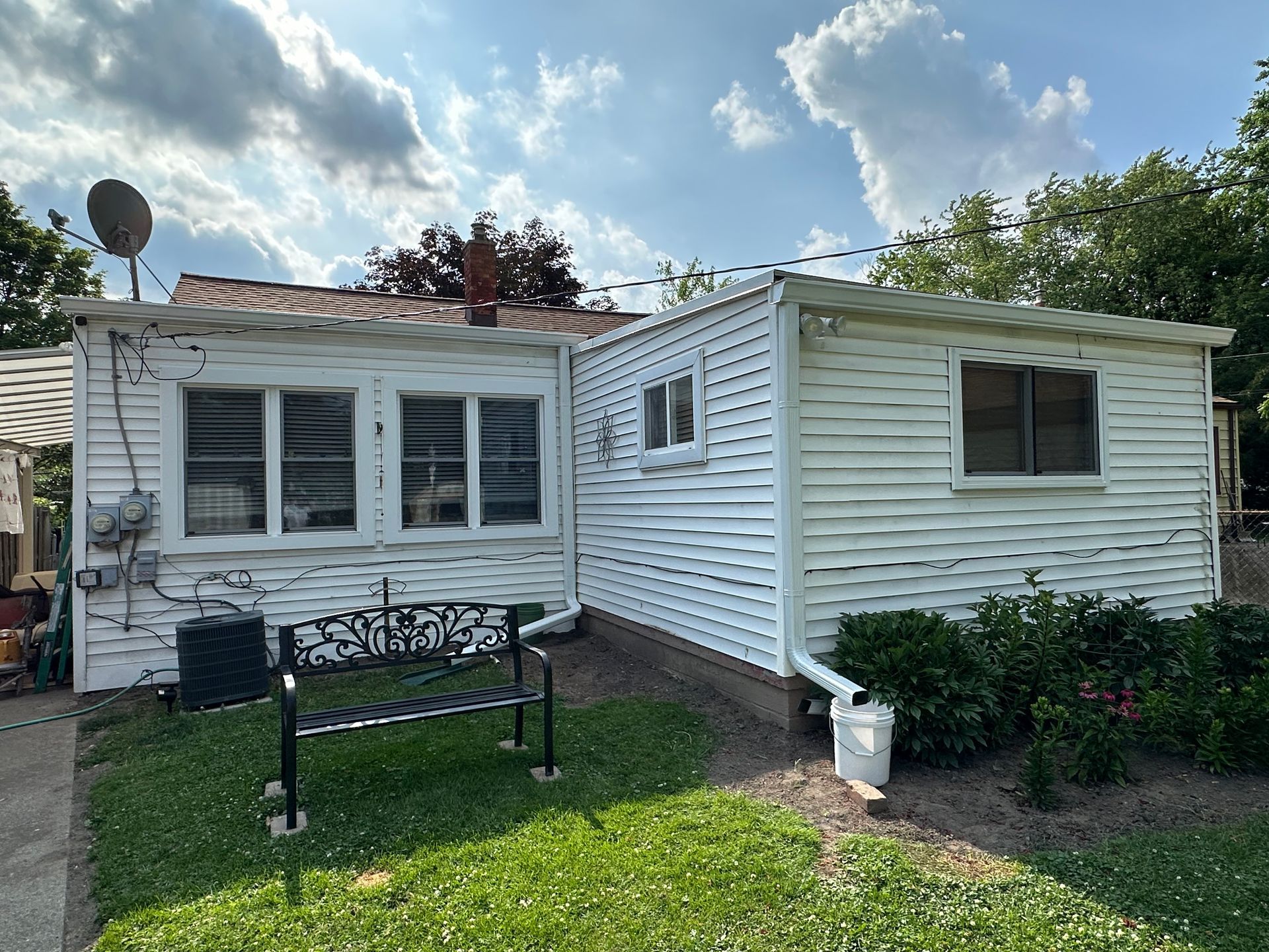 White house with bench in yard; sunny day.