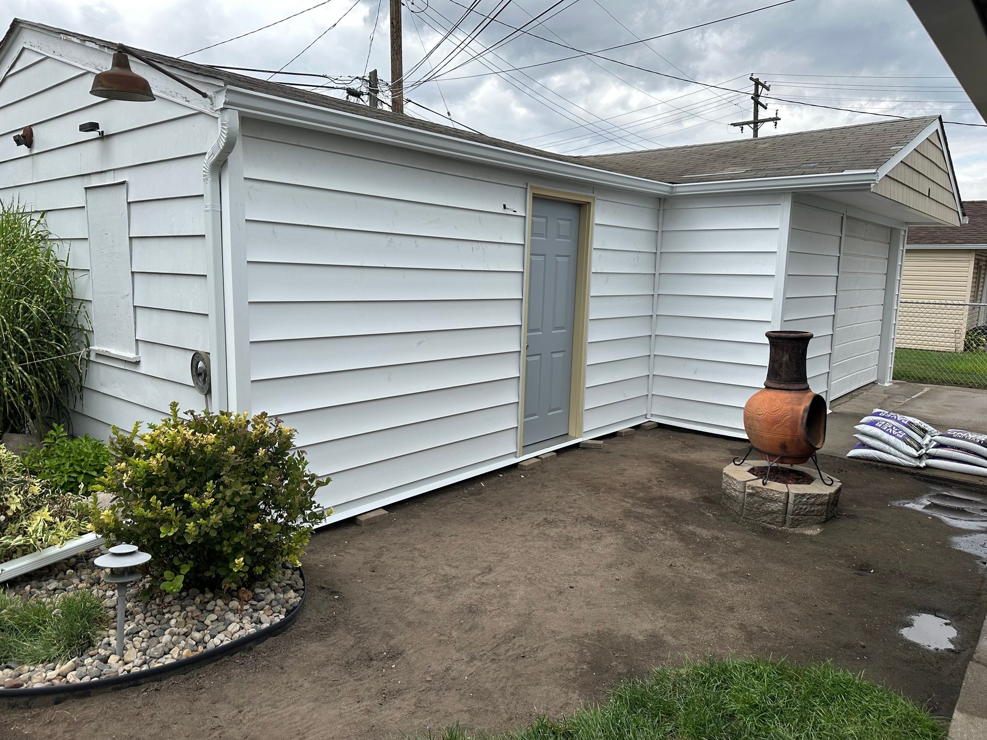 White garage with gray door, brown chimney, and landscaping.