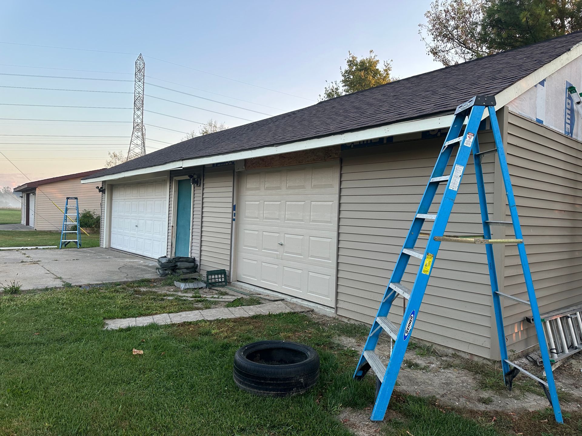 Garage with blue ladder, brown siding, and black tire.
