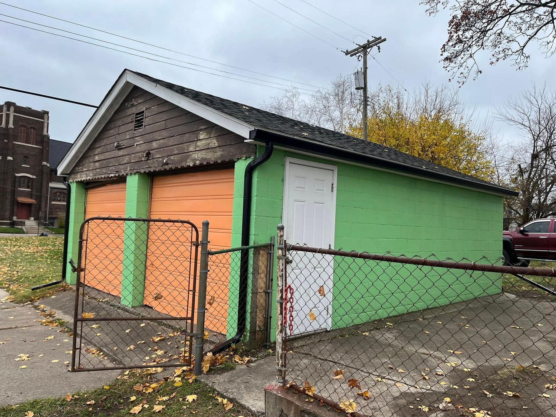 Two-car garage with orange doors and green walls, with a chain link fence.