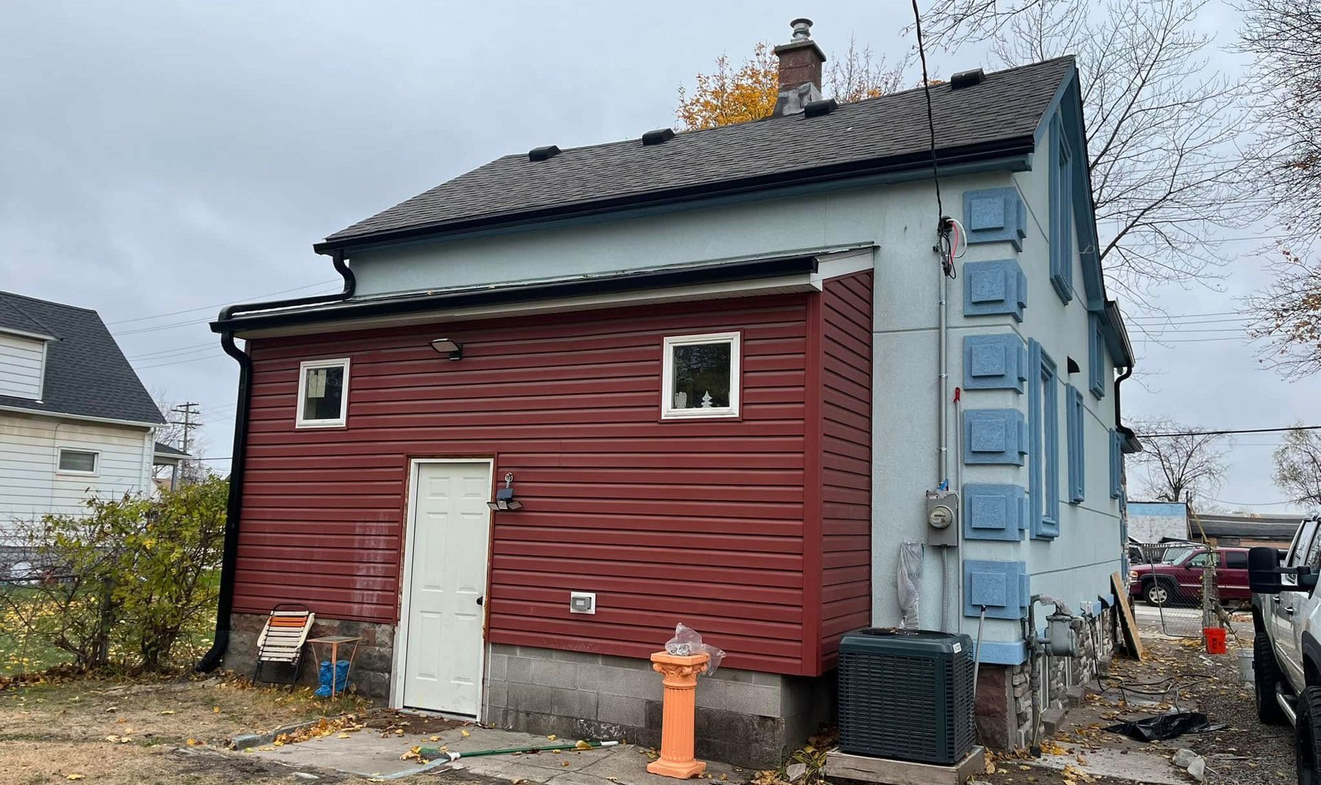 Red and blue building with multiple windows and light blue shutters. A fire hydrant is in front.