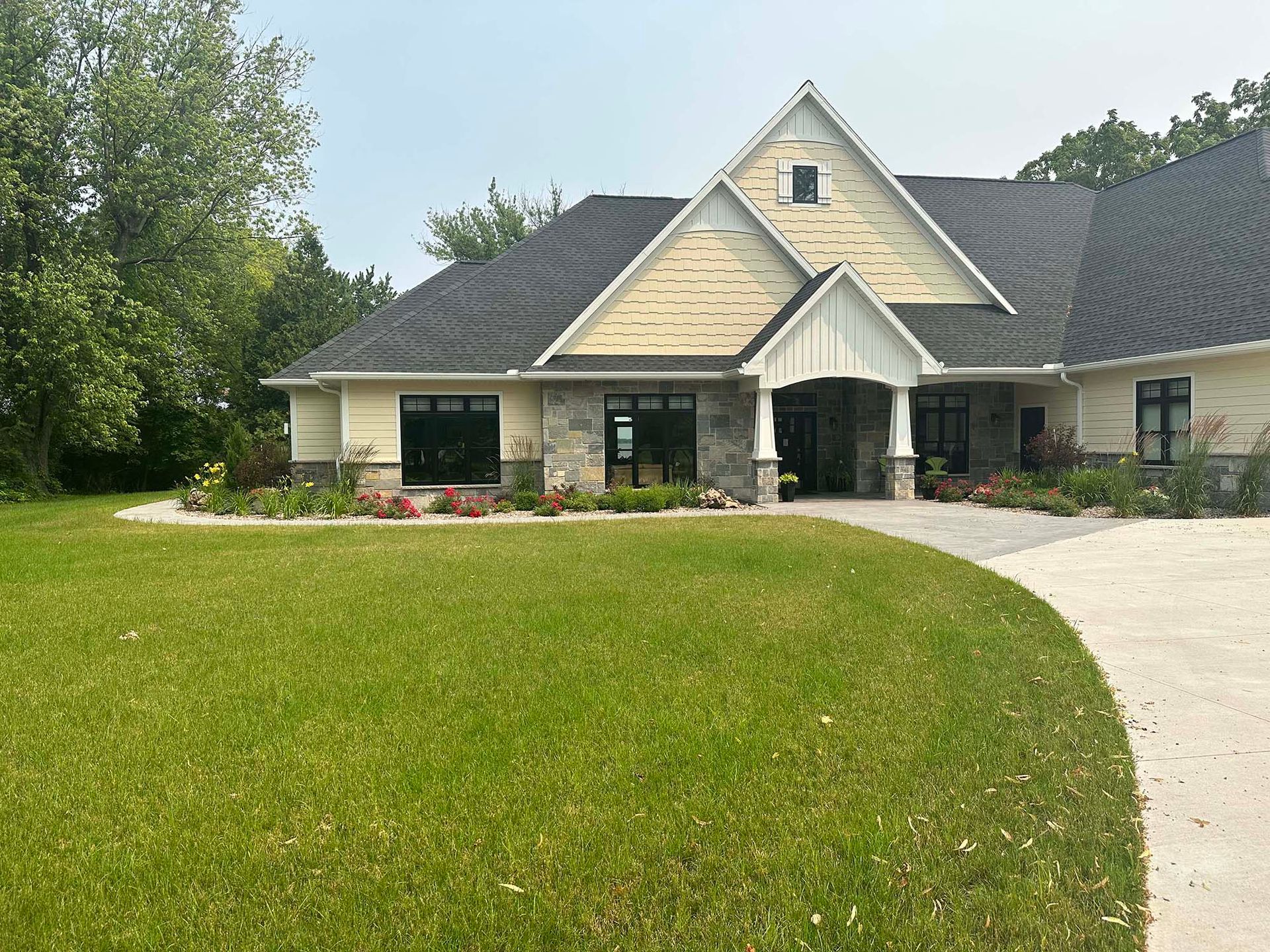 A large house with a lush green lawn and a driveway leading to it.
