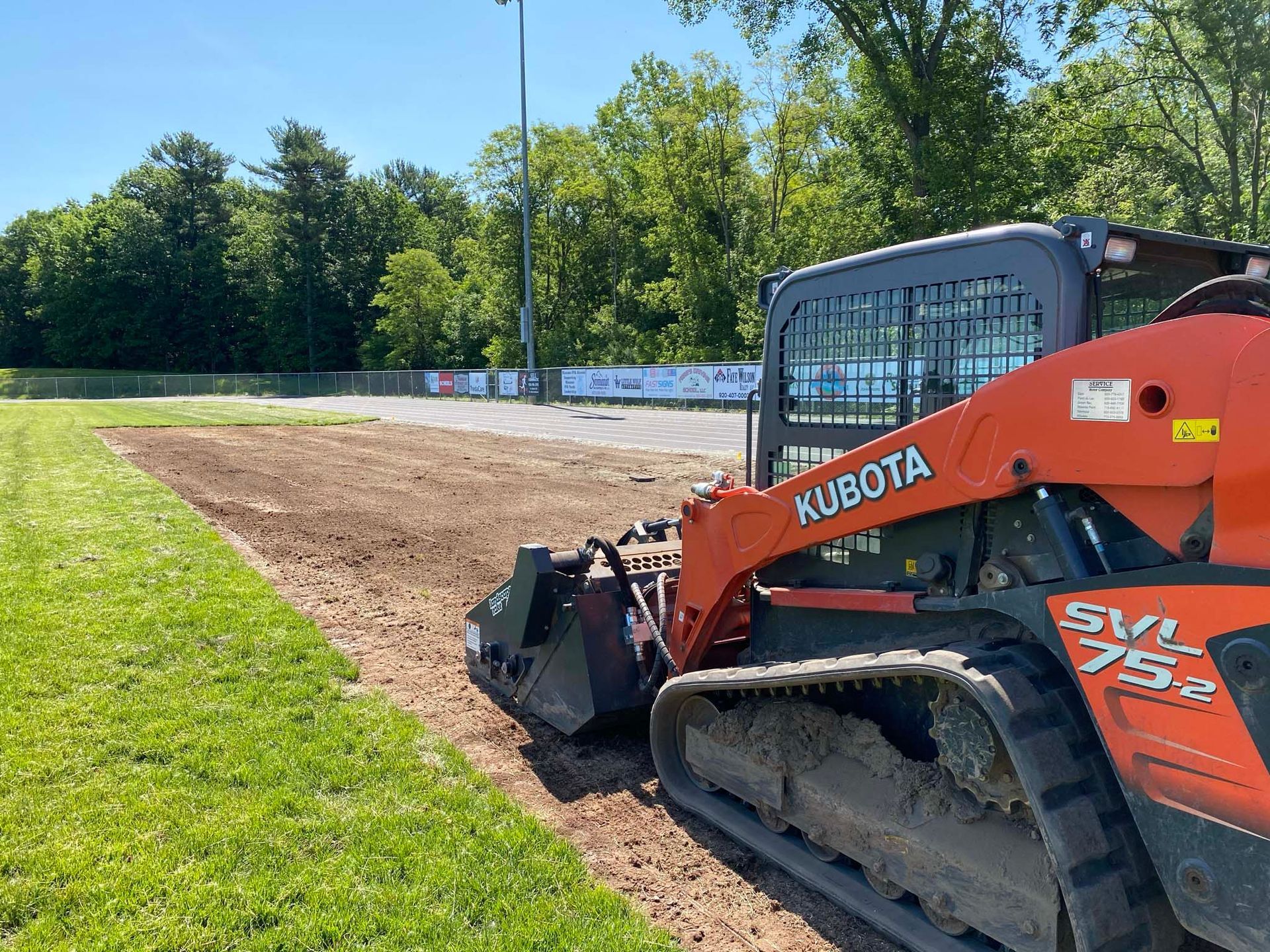 A kubota skid steer is moving dirt in a field.
