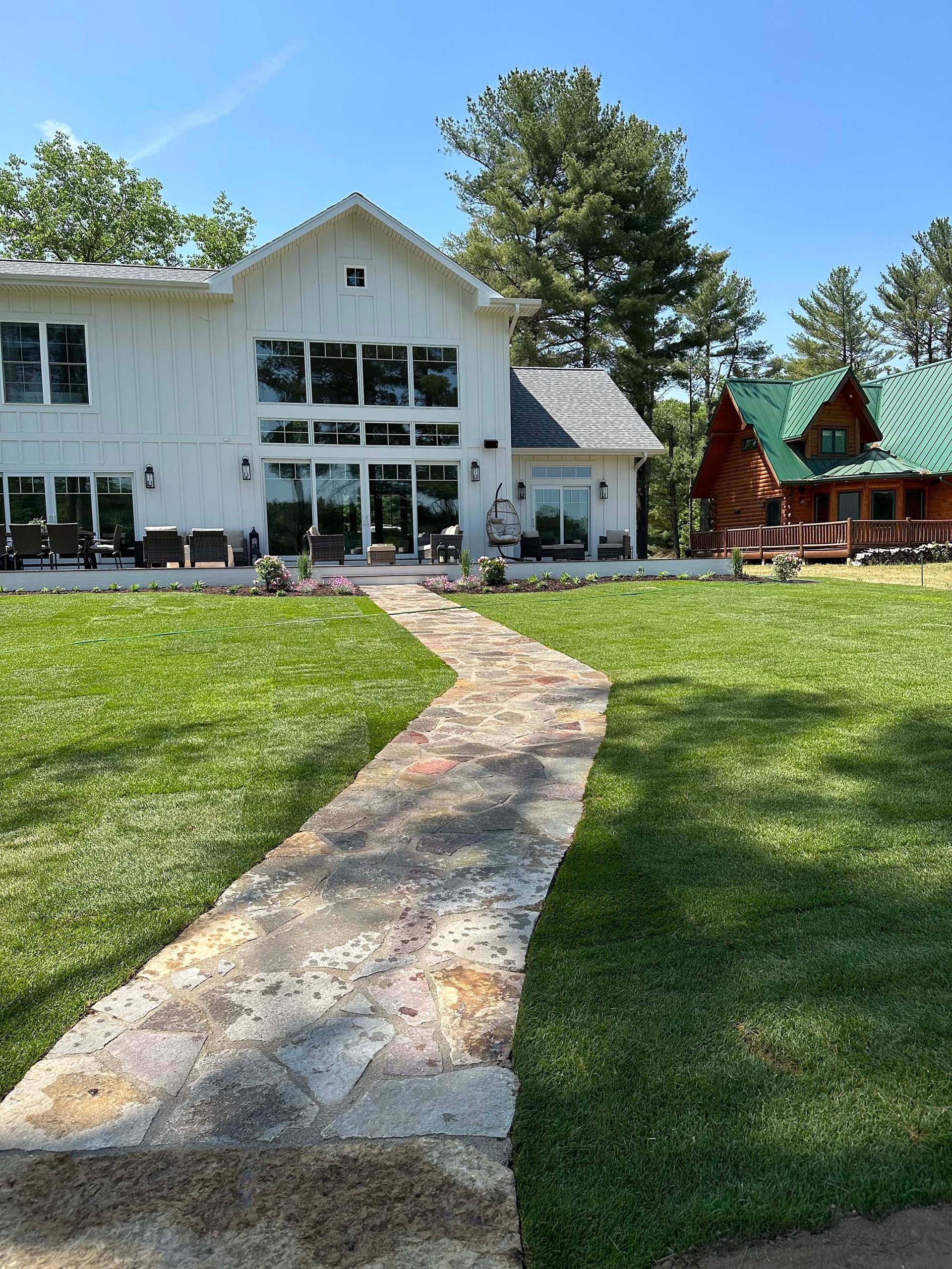 A large white house with a green roof and a stone walkway leading to it.
