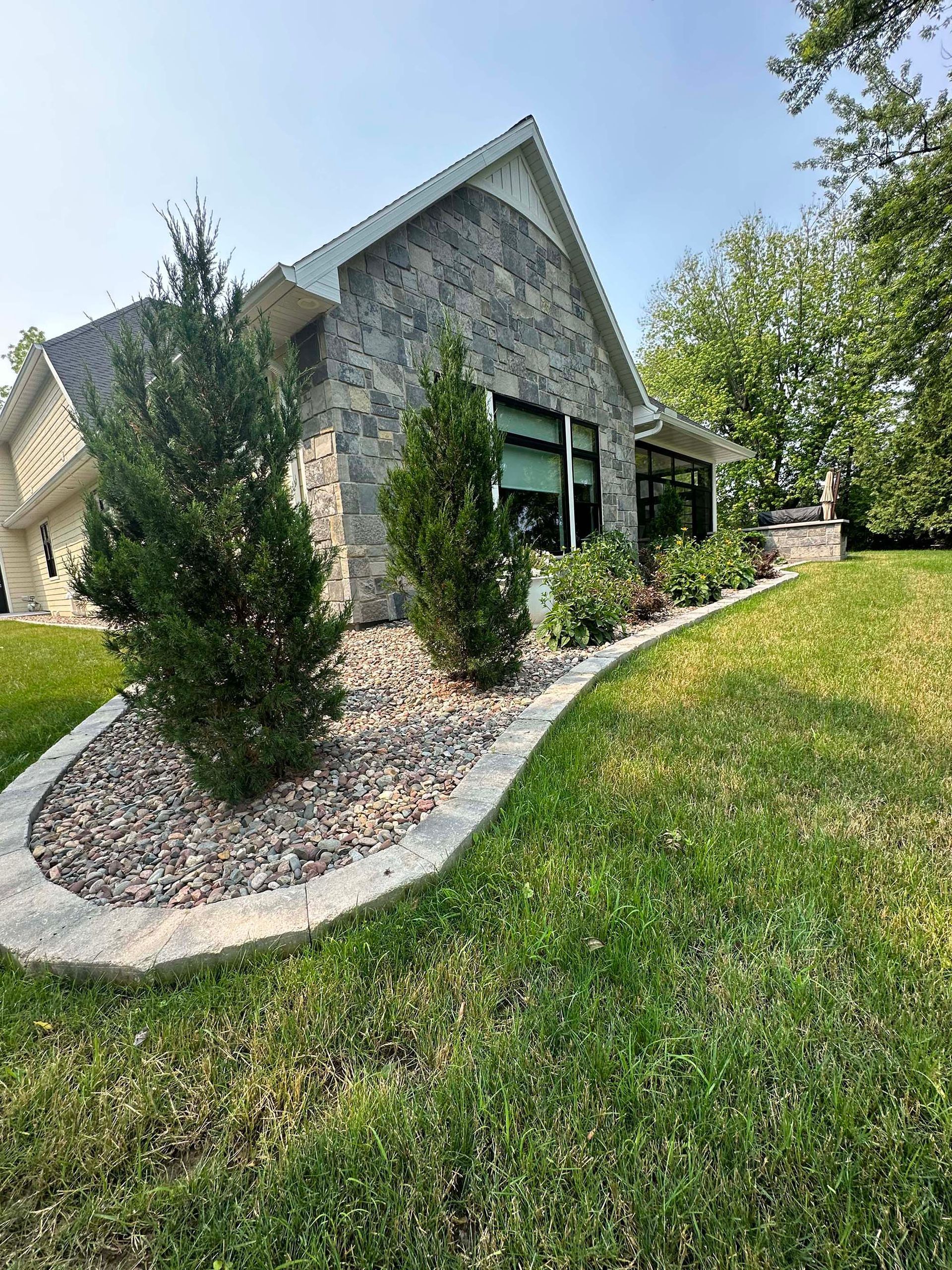 A large stone house with a lush green lawn in front of it.