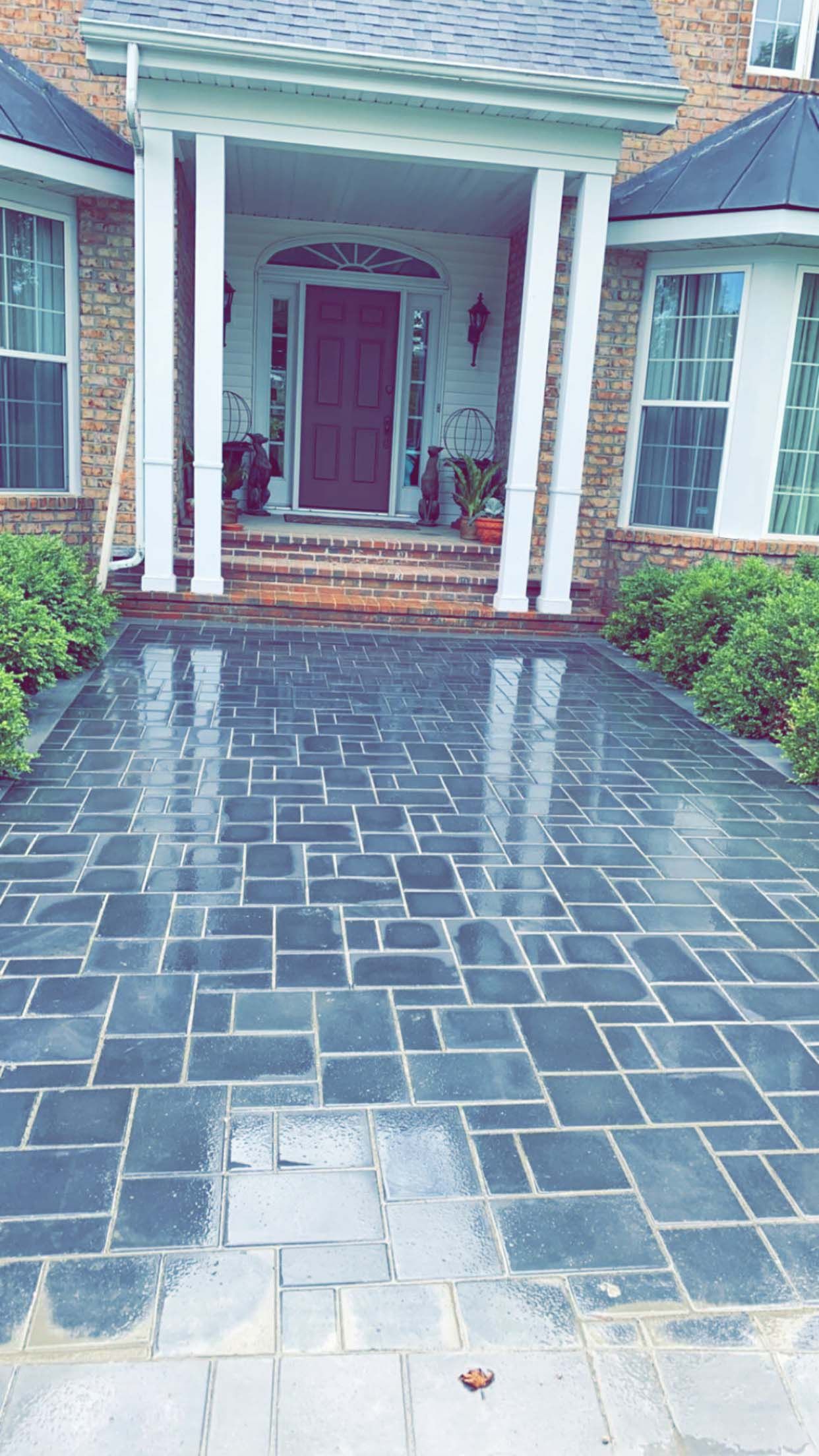 A brick driveway leading to the front door of a house.