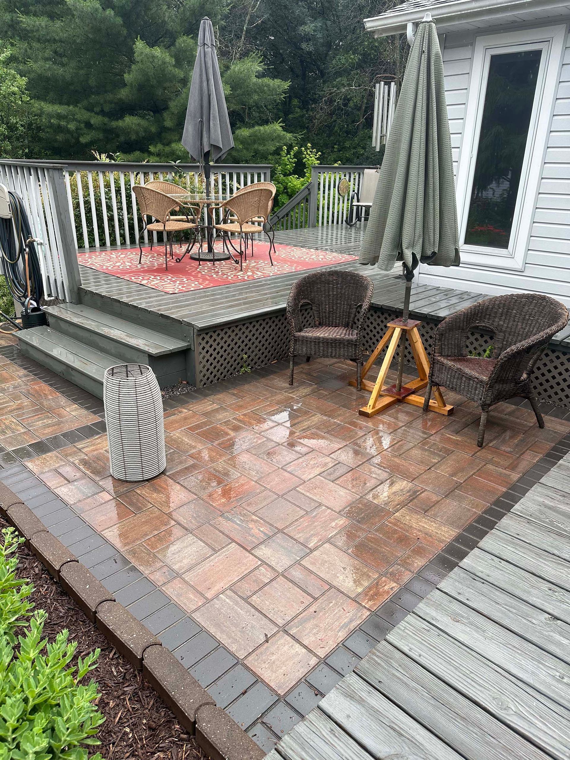 A patio with wicker furniture and umbrellas in front of a house.