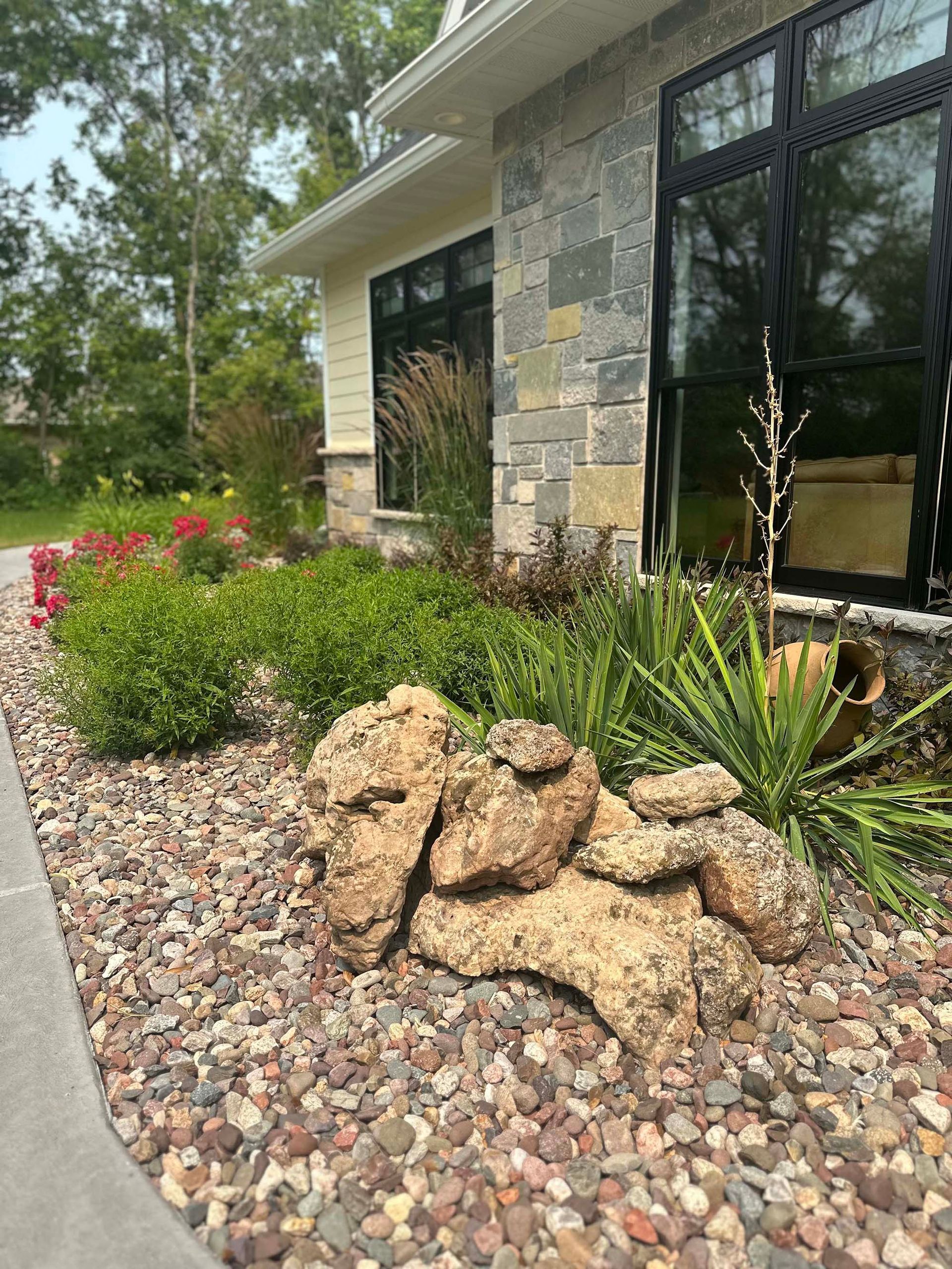 A house with a lot of rocks and plants in front of it.
