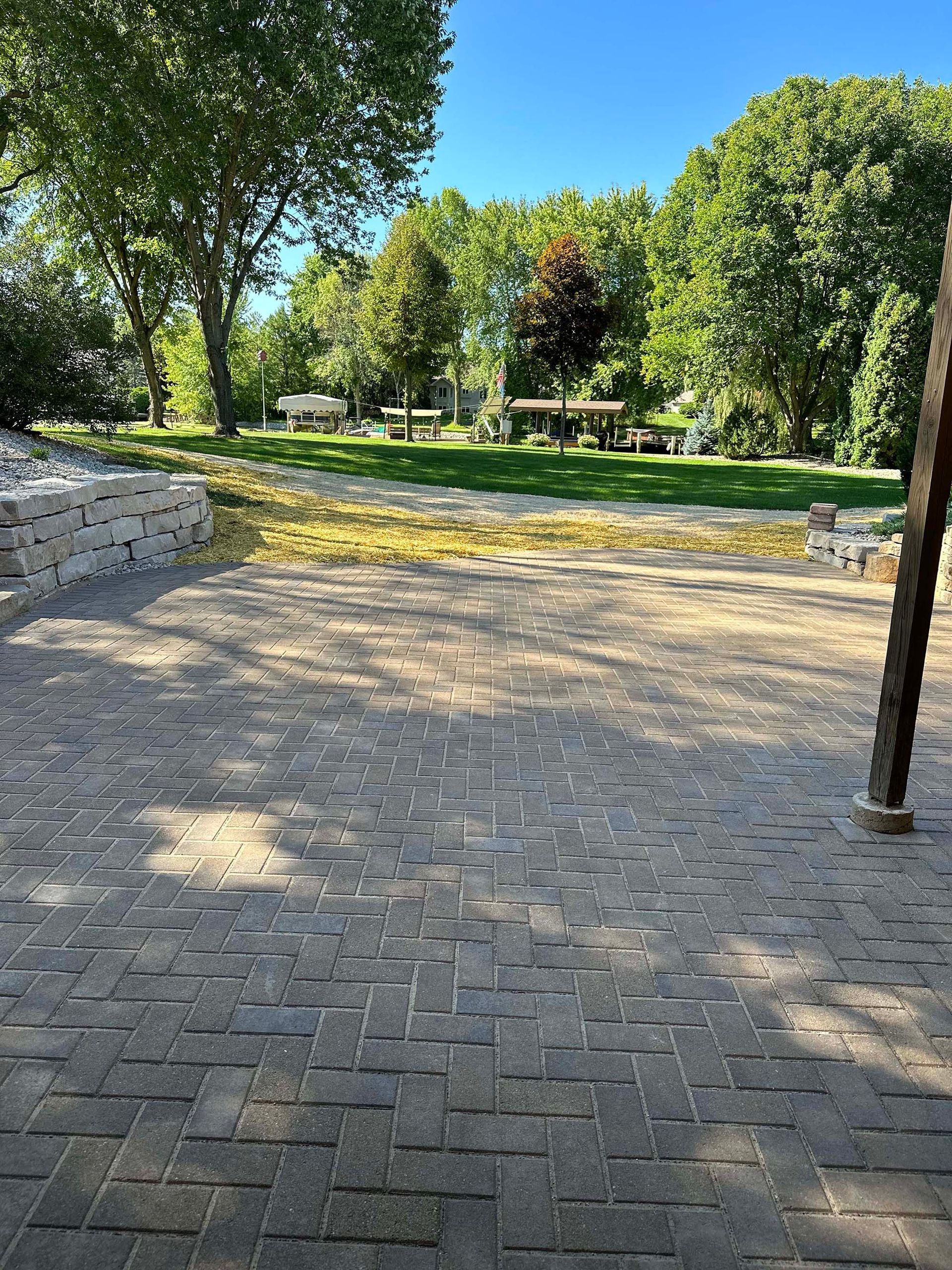 A brick walkway leading to a park with trees in the background
