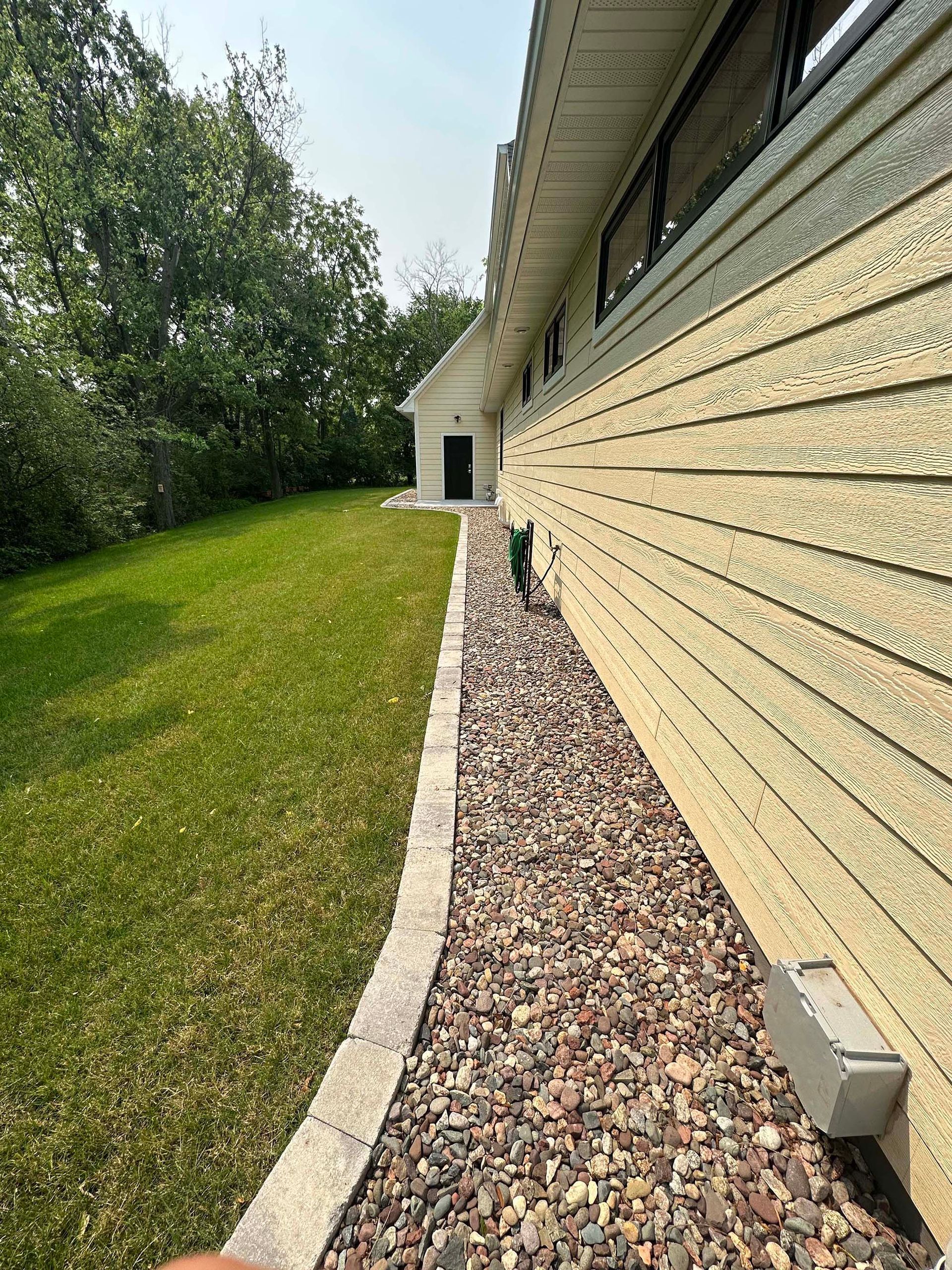 A sidewalk leading to a house with gravel and grass.