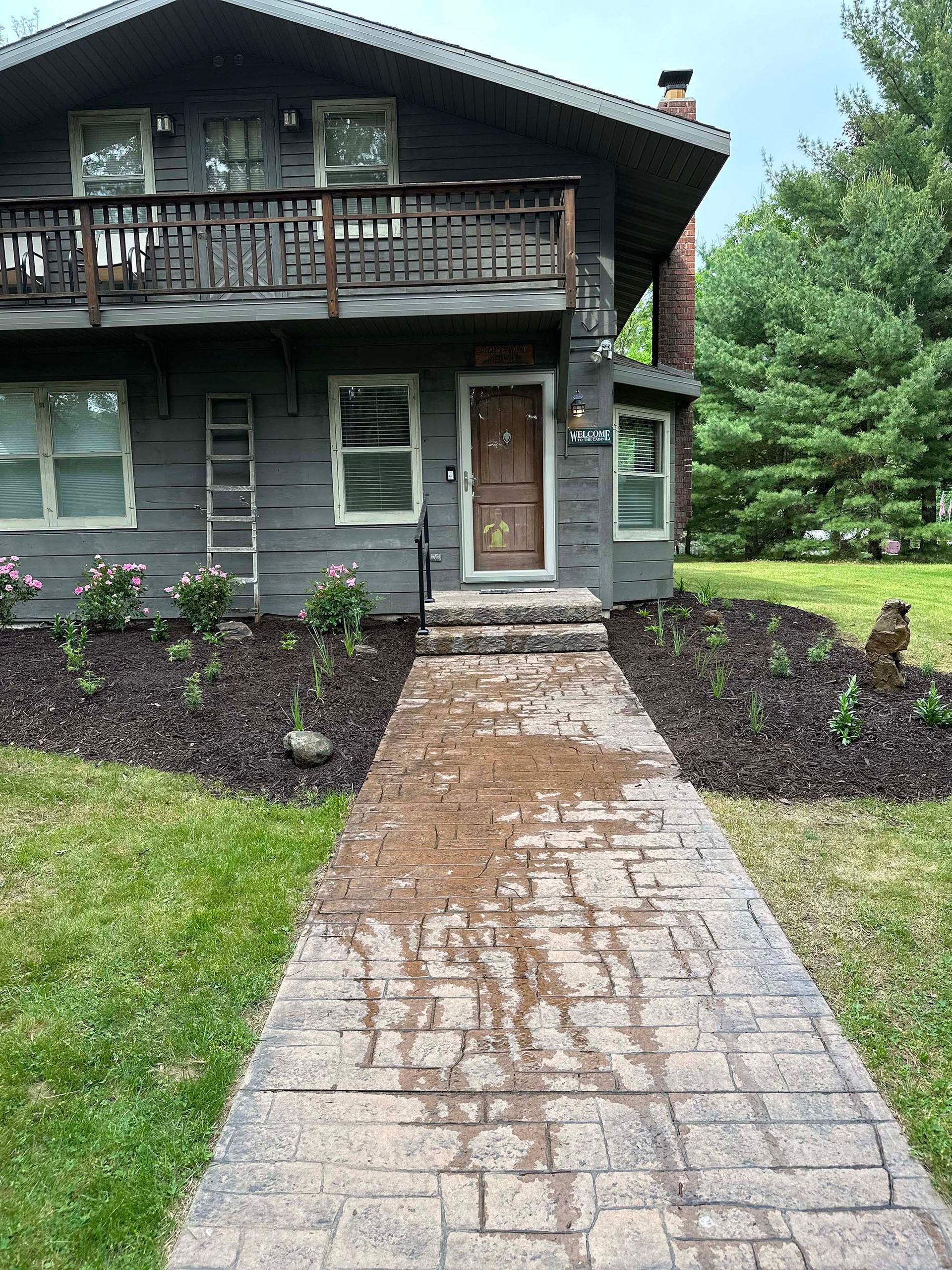 There is a brick walkway leading to the front of the house.