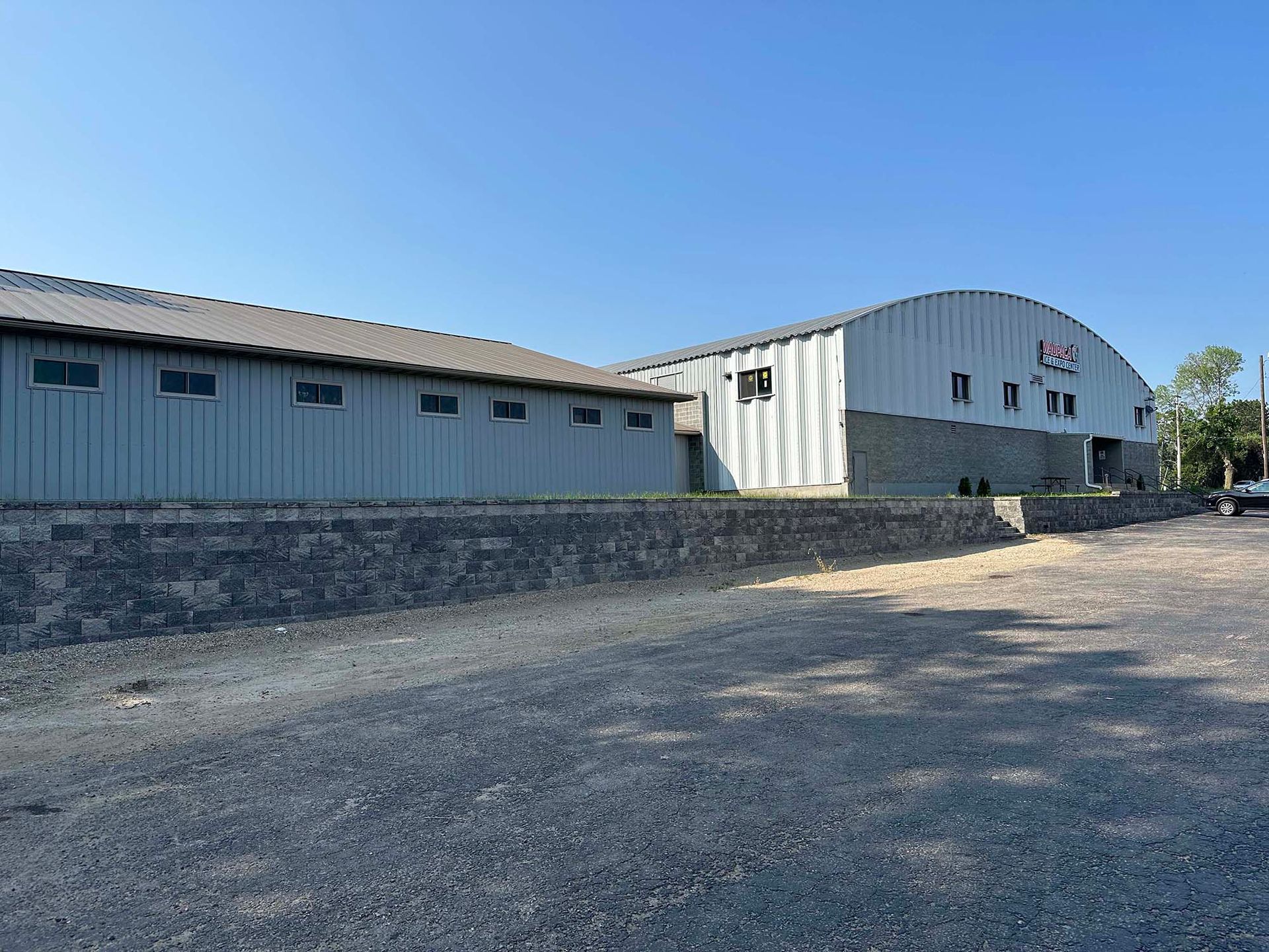 A large building with a lot of windows is sitting next to a gravel road.