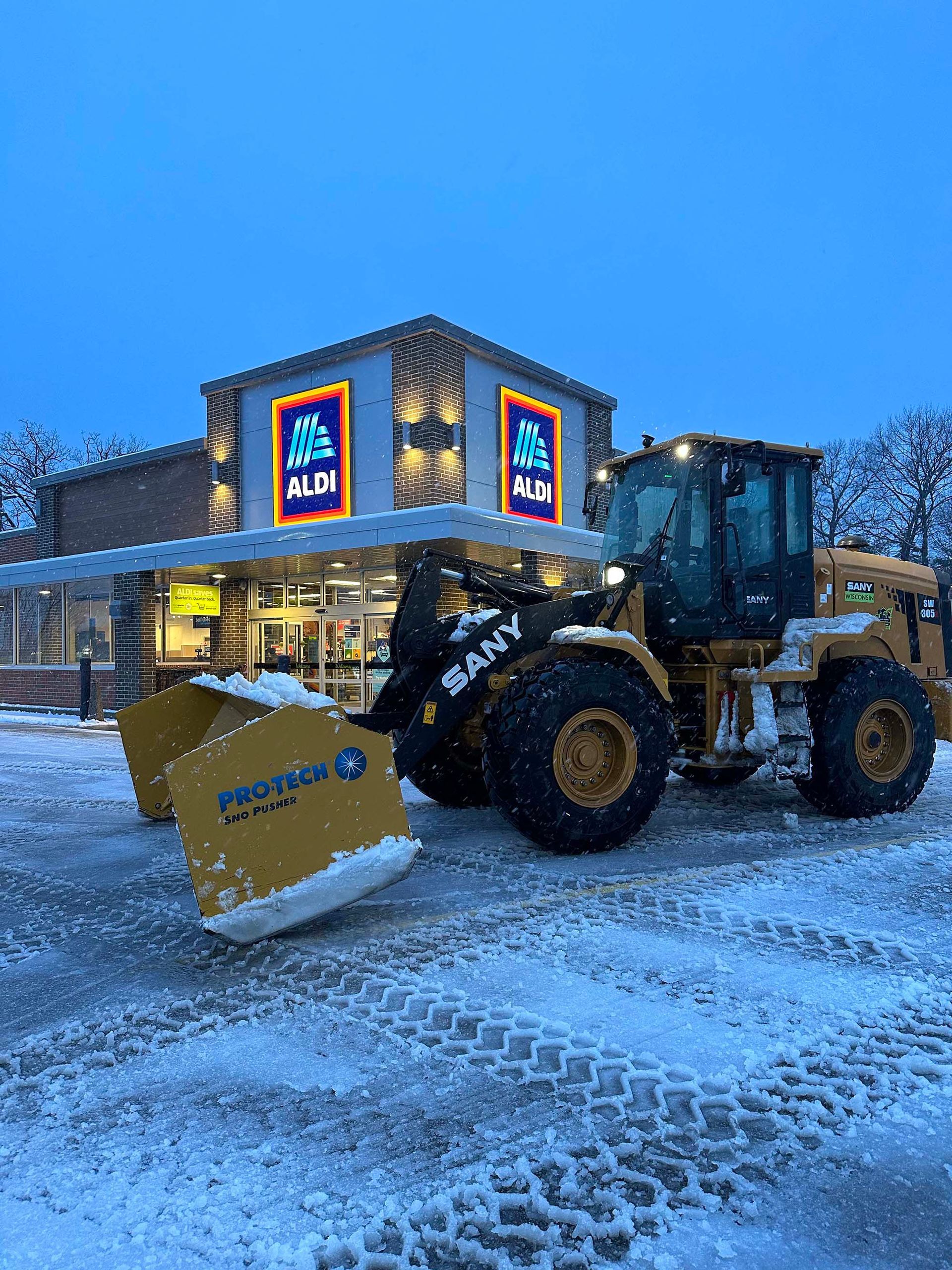 A tractor is plowing snow in front of a store.