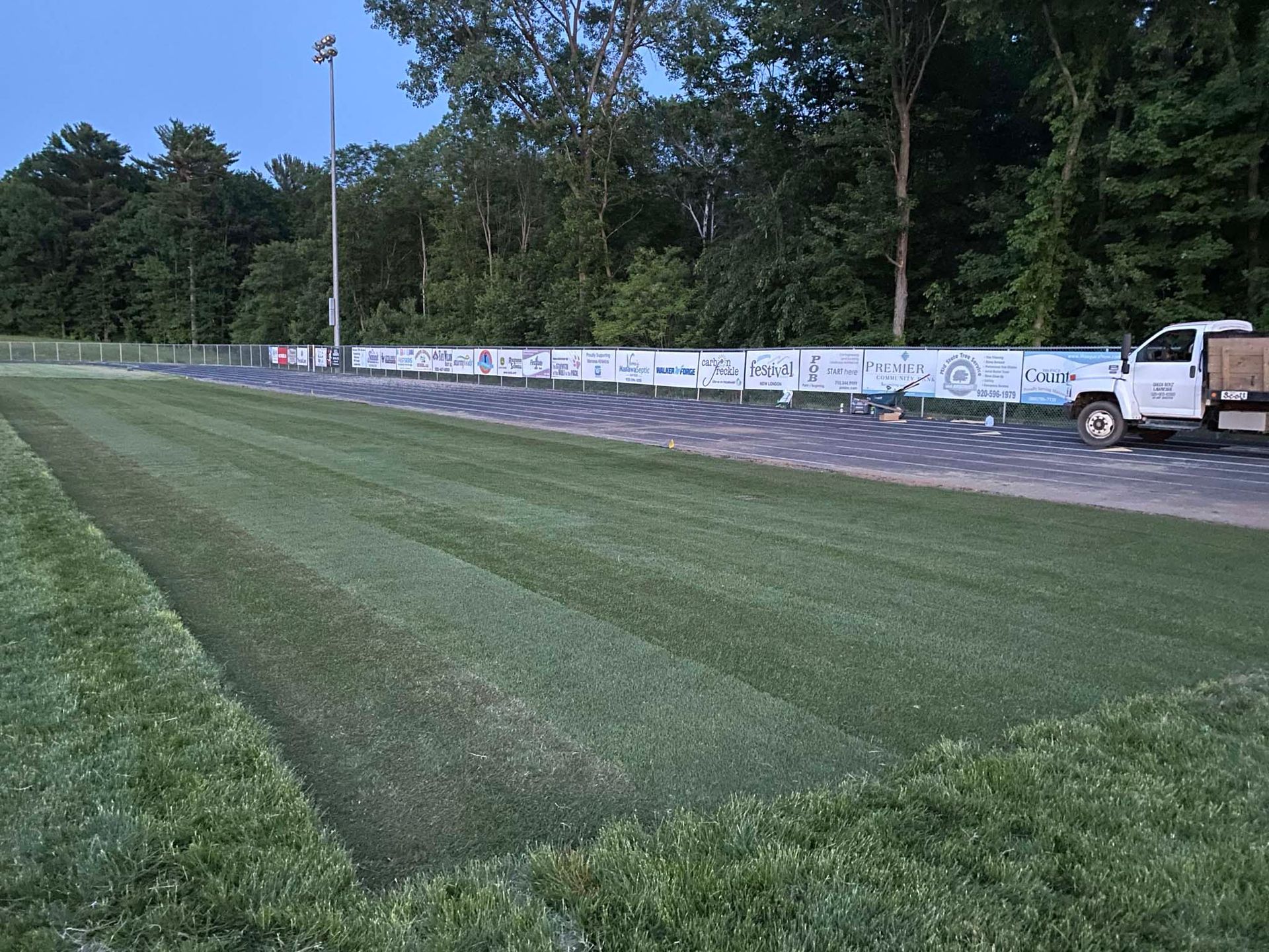 A white truck is parked on the side of a lush green field