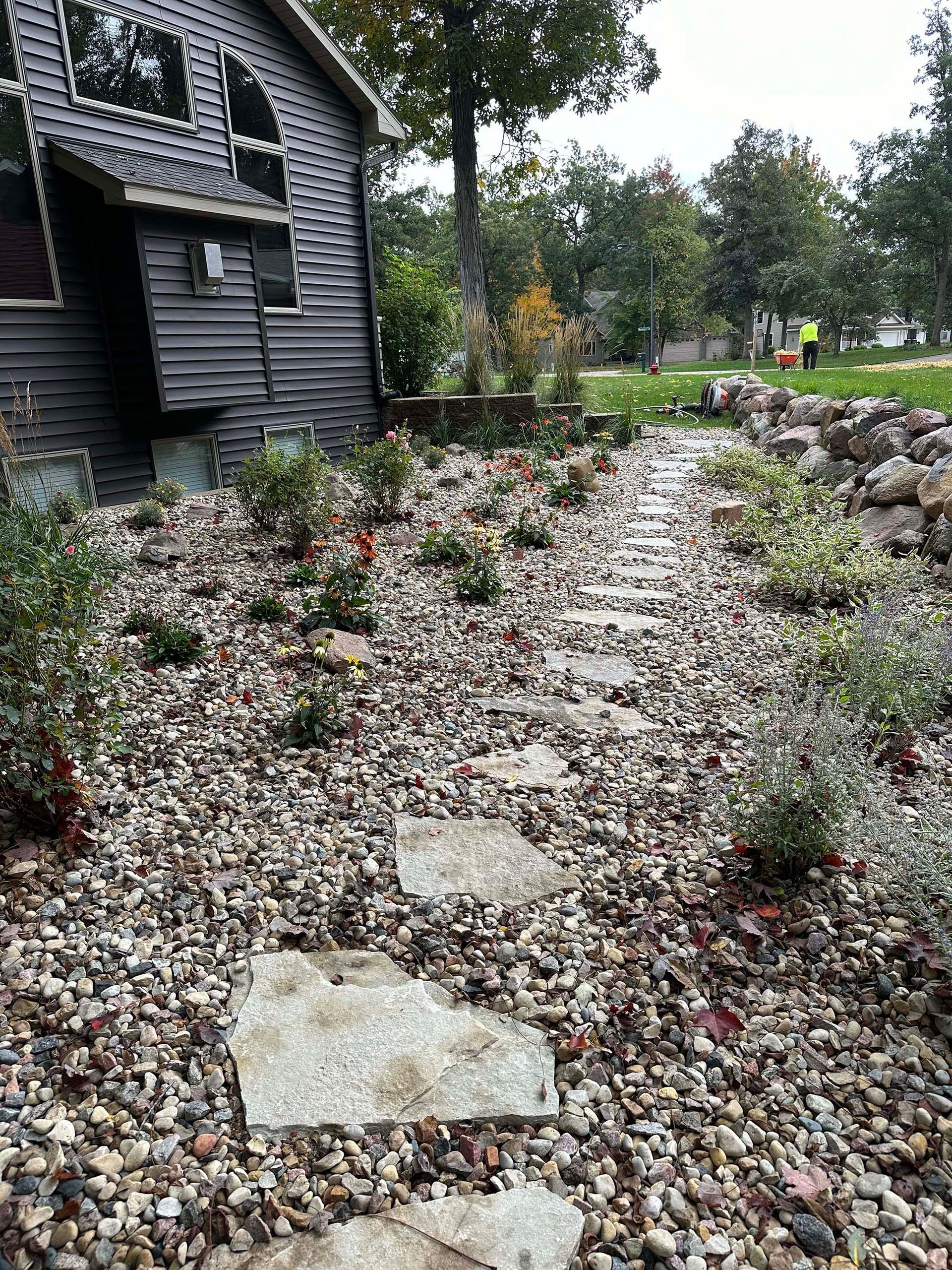 A path leading to a house surrounded by rocks and plants.