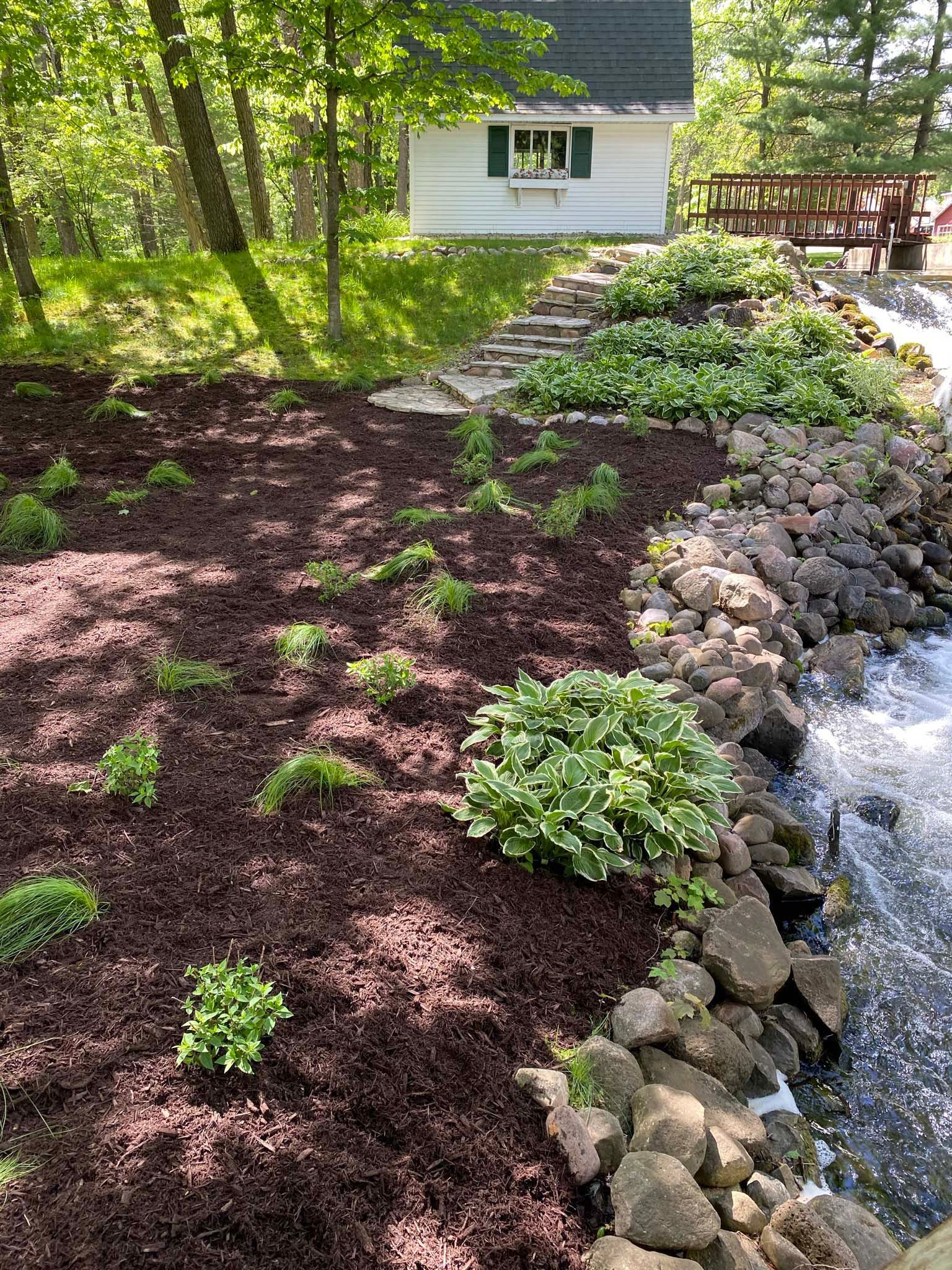 There is a small house in the background and a stream running through the yard.