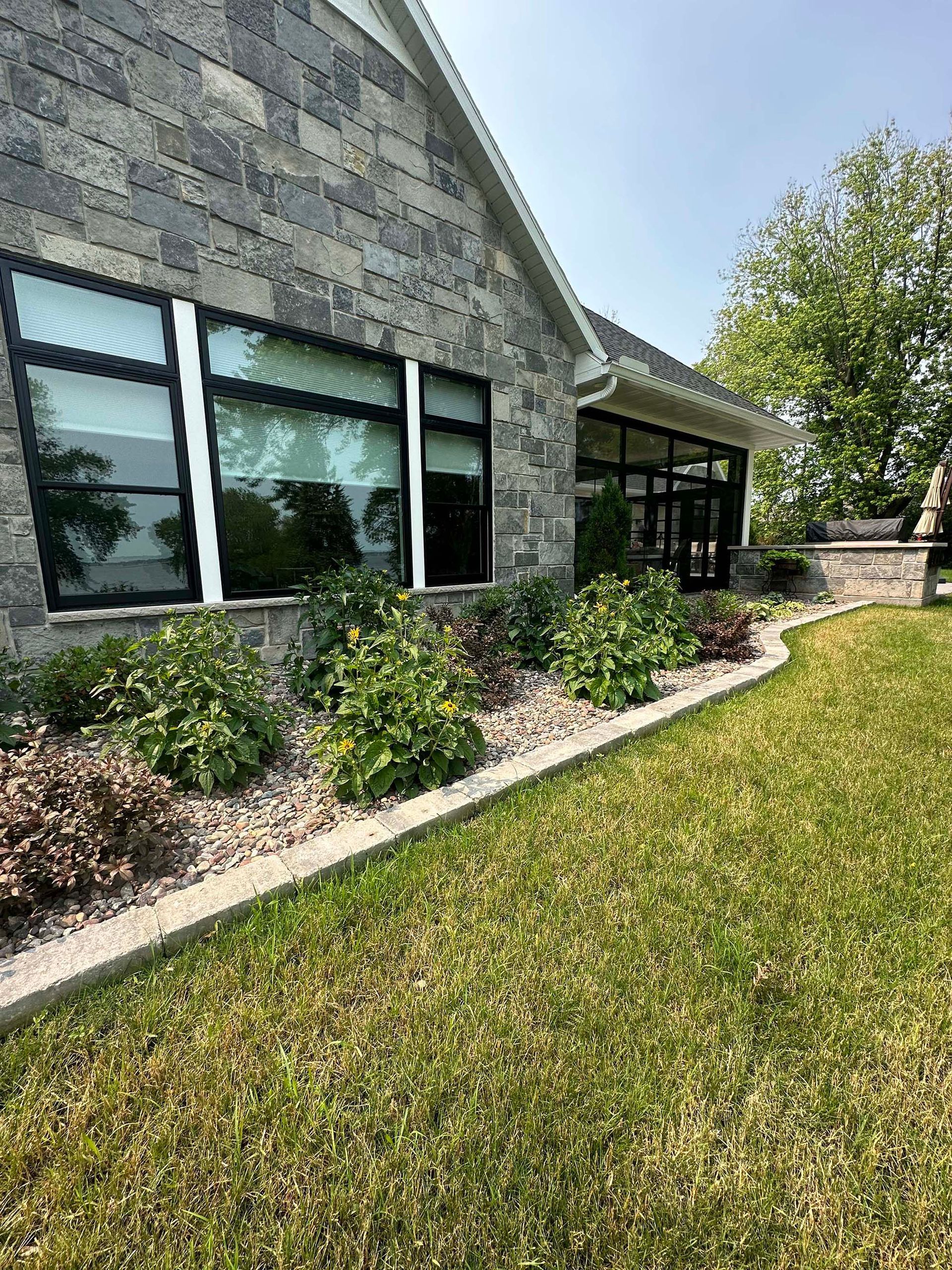 A large brick building with a lot of windows and a lush green lawn in front of it.