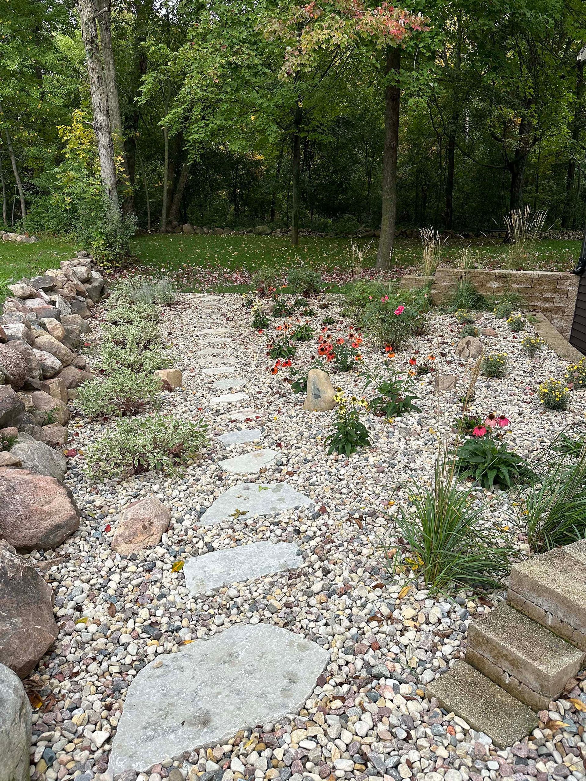 A rock garden with flowers and trees in the background.