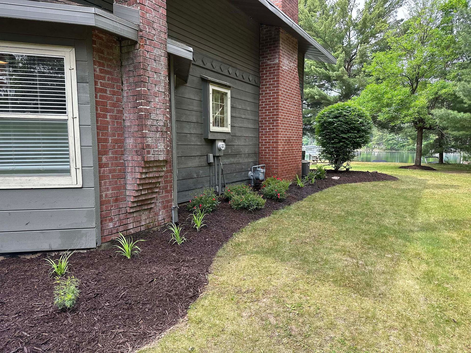 A brick house with a lush green lawn in front of it.
