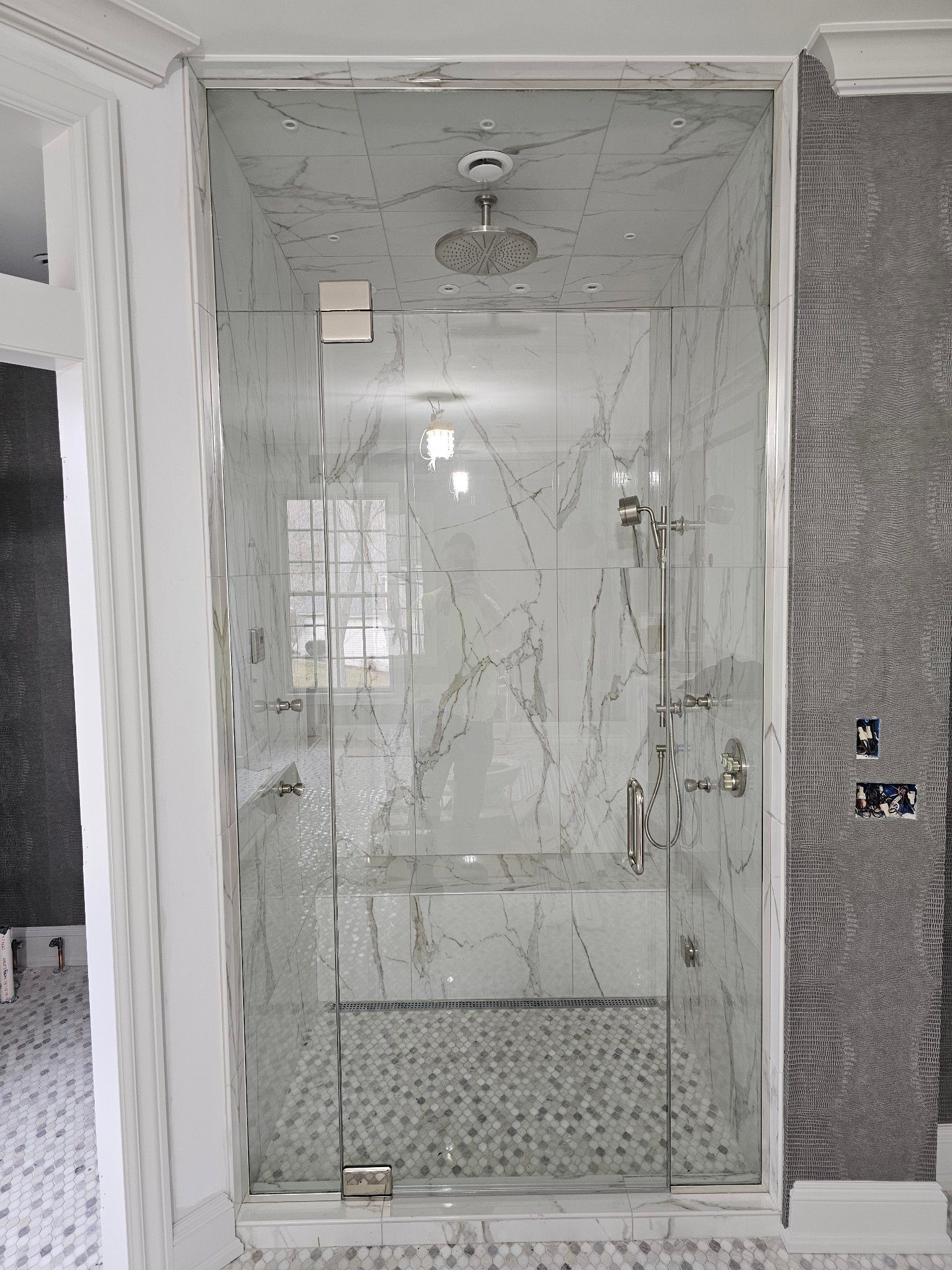 A bathroom with a walk in shower with a glass door.
