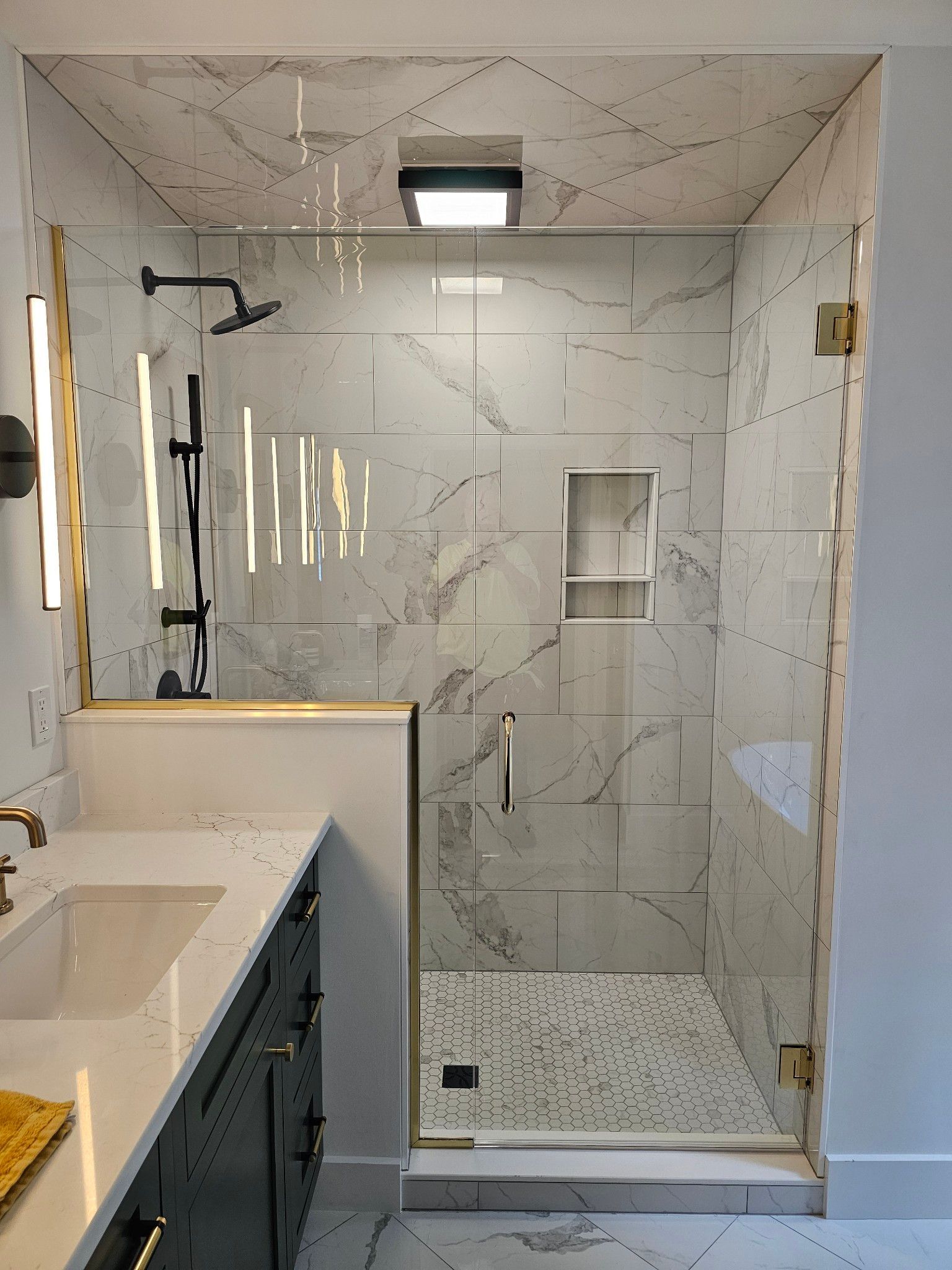 A bathroom with a walk in shower and a sink