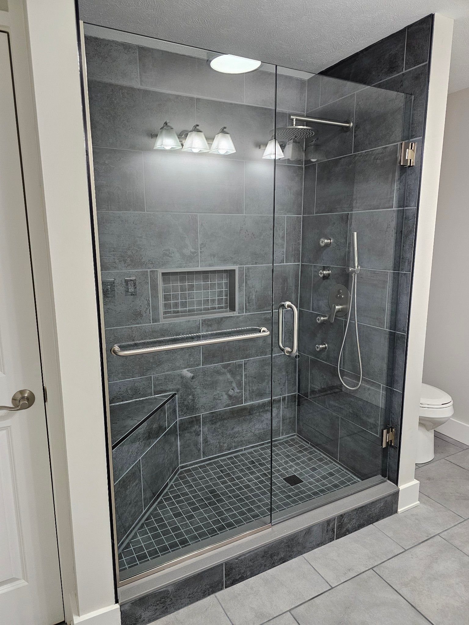 A bathroom with a walk in shower with a glass door.