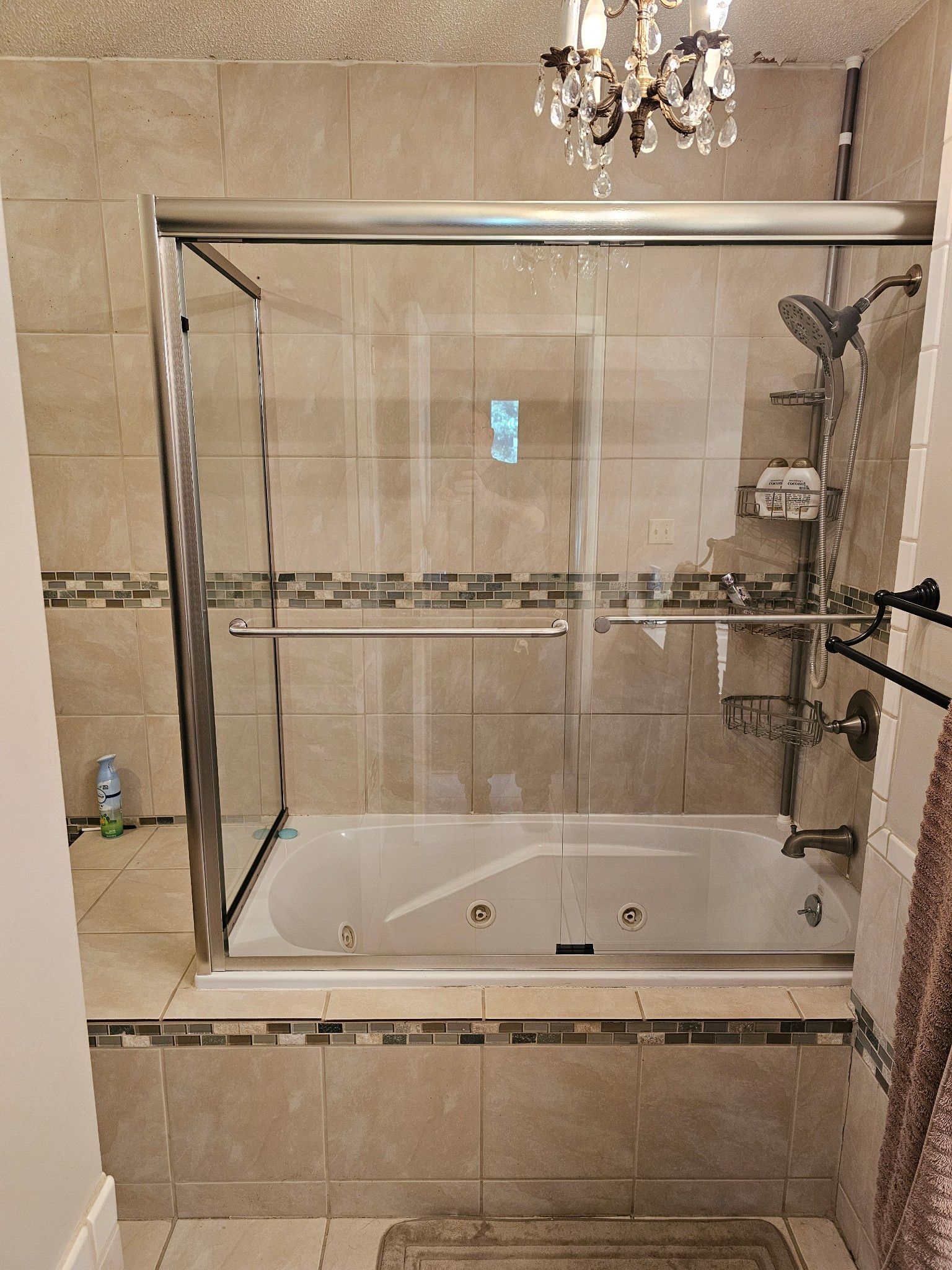 A bathroom with a tub , shower , and chandelier.