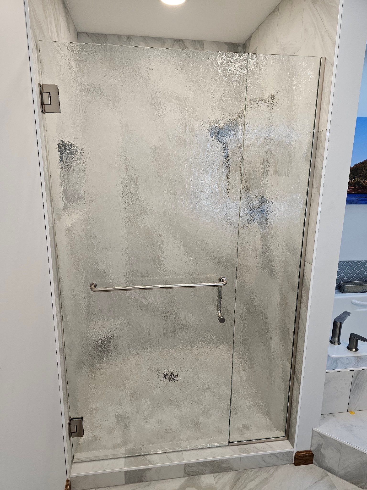 A bathroom with a walk in shower with a glass door.