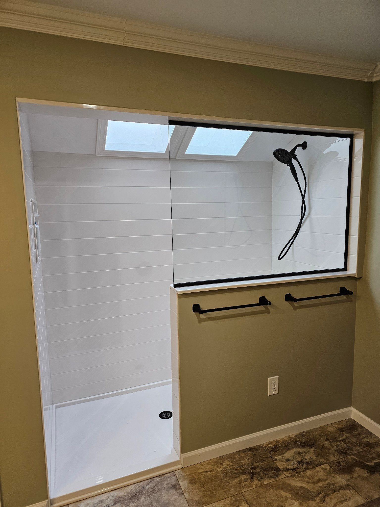 A bathroom with a walk in shower and a window.