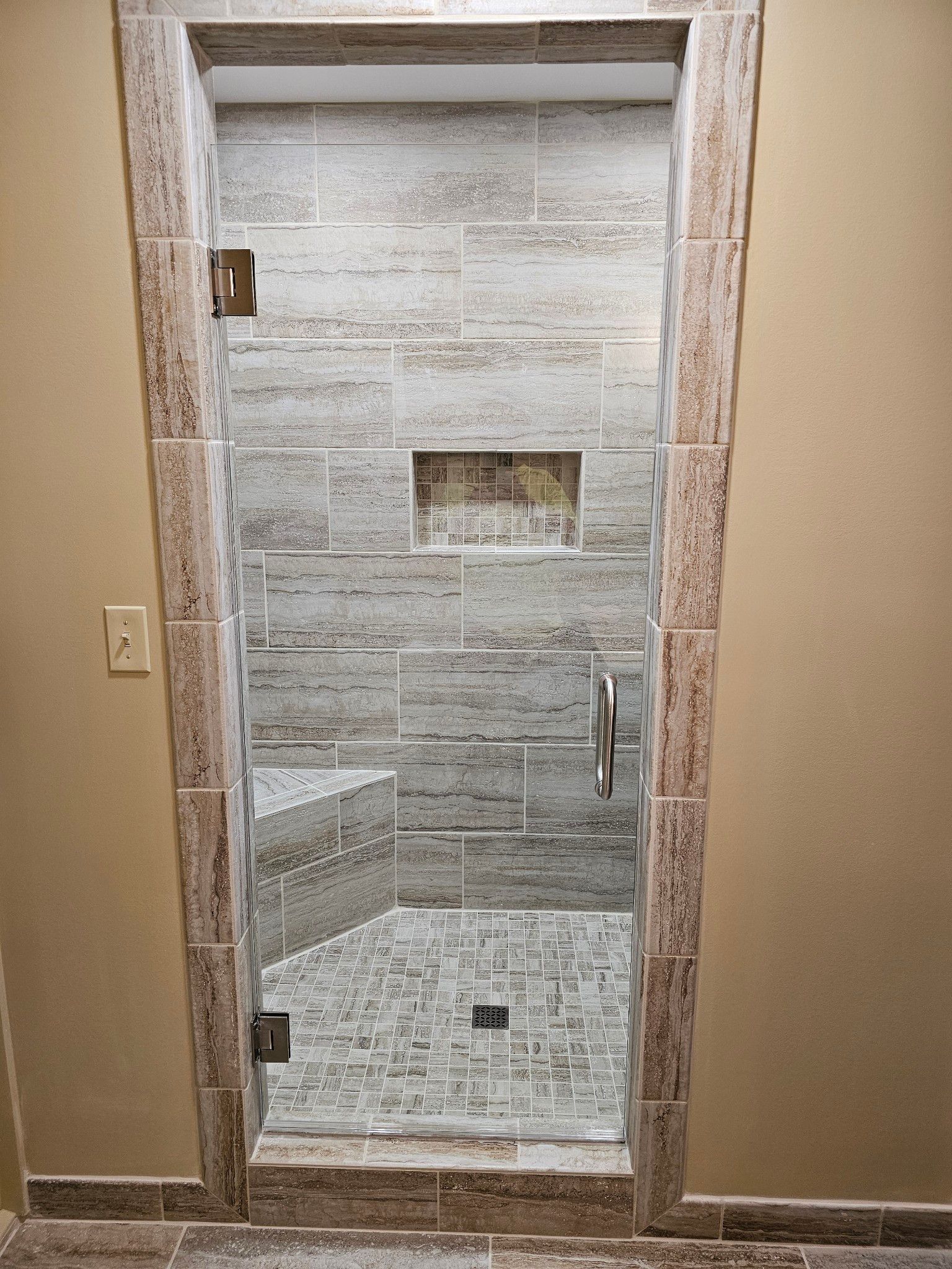 A bathroom with a walk in shower with a glass door.