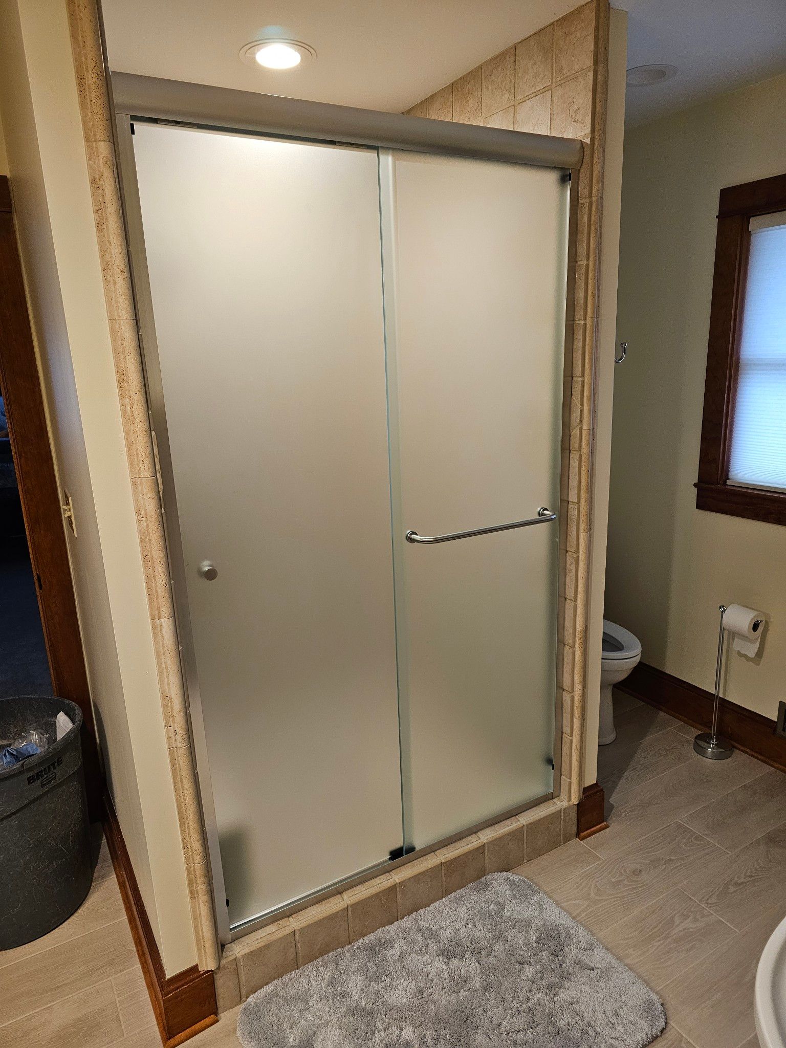 A bathroom with a sliding glass shower door and a toilet.
