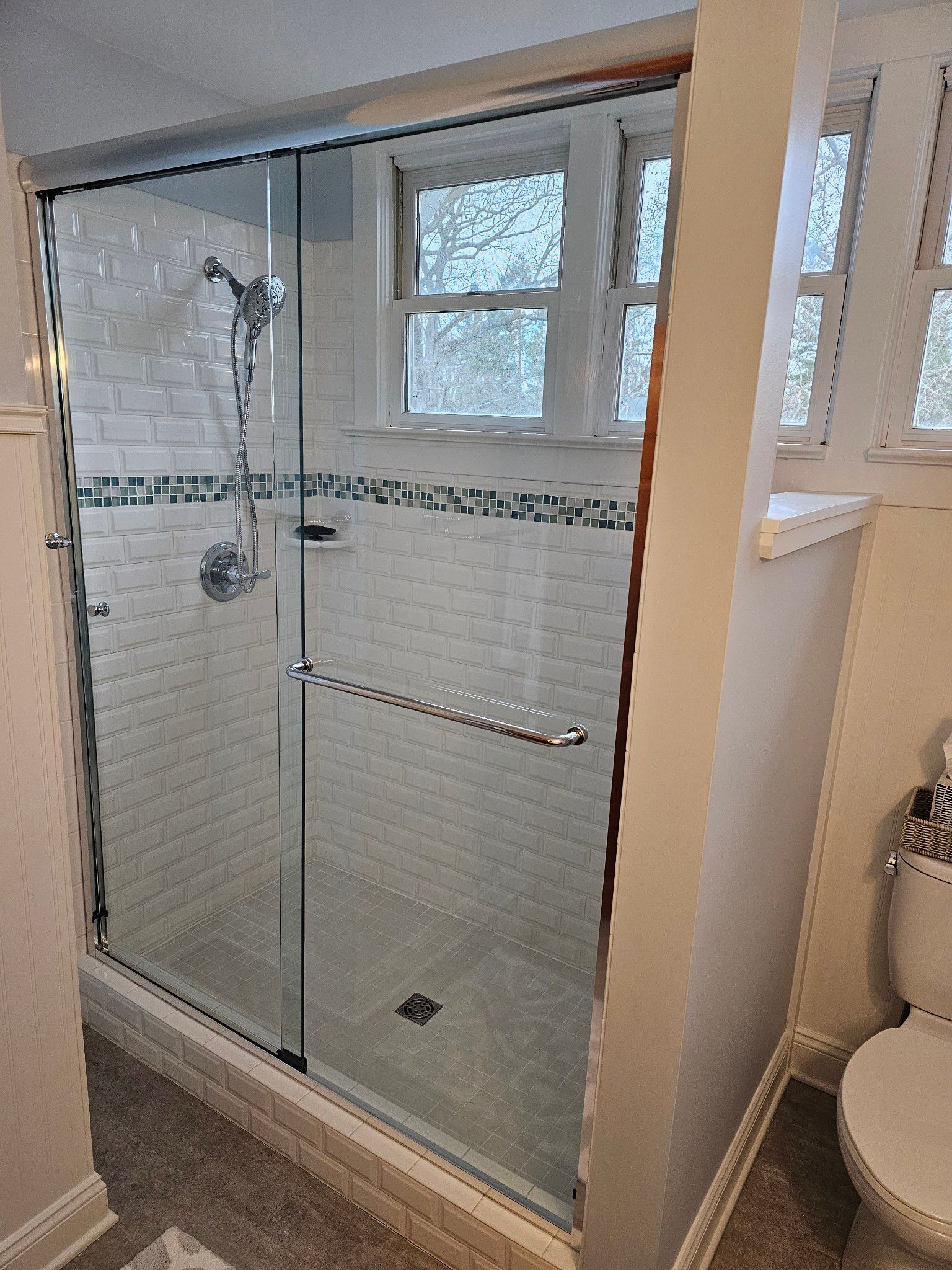 A bathroom with a sliding glass shower door and a toilet.