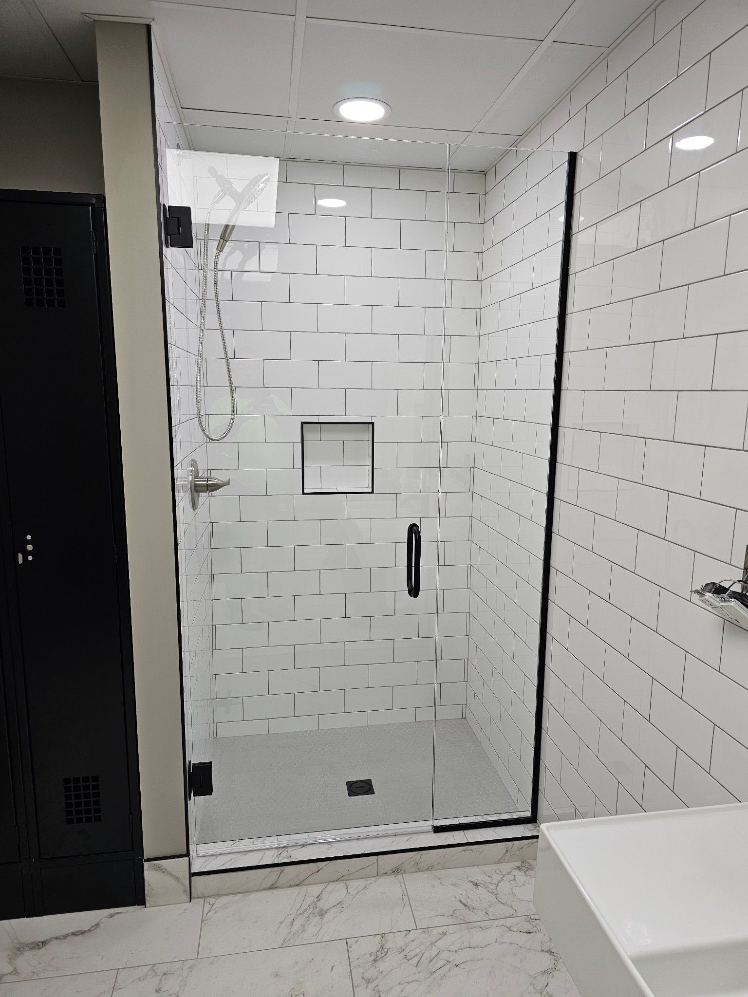 A bathroom with a walk in shower and a sink