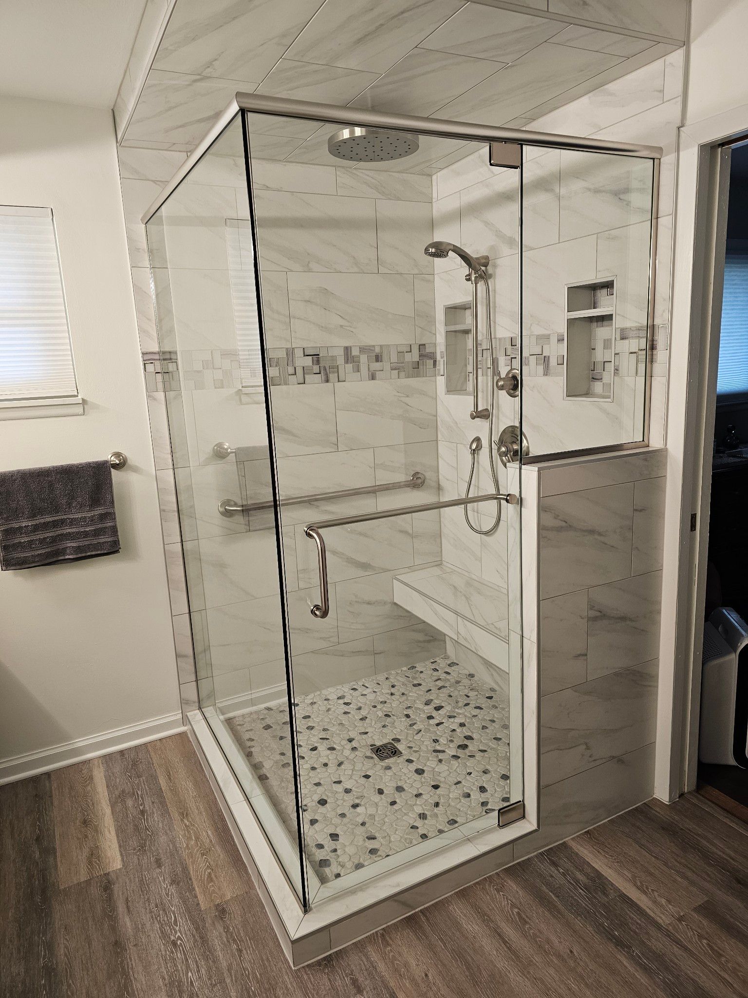 A bathroom with a walk in shower with a glass door.