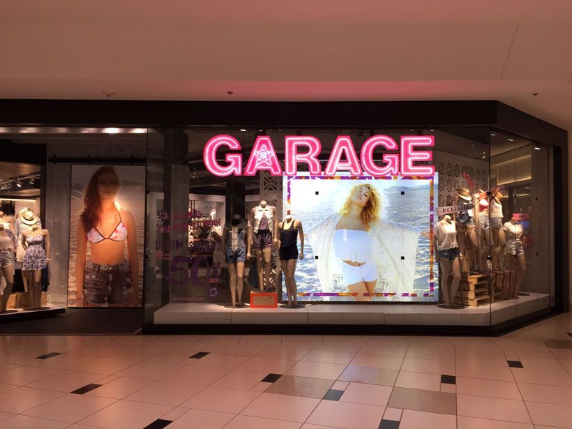 A garage store in a shopping mall with mannequins in front of it.