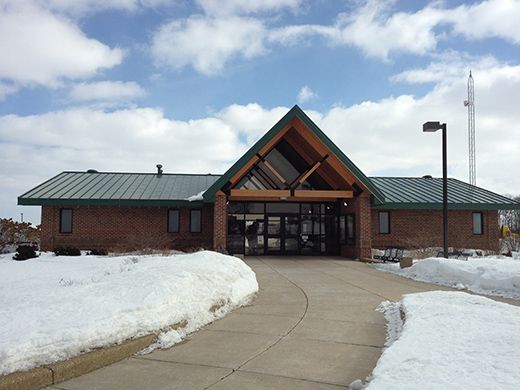 A brick building with a green roof is surrounded by snow
