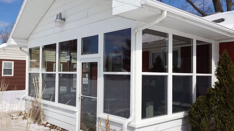 A white house with a screened in porch and a lot of windows.