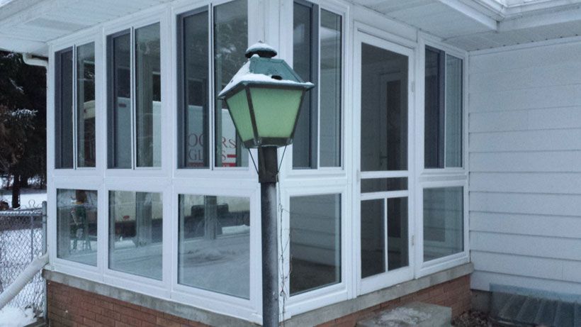 There is a lamp post in front of a screened in porch.