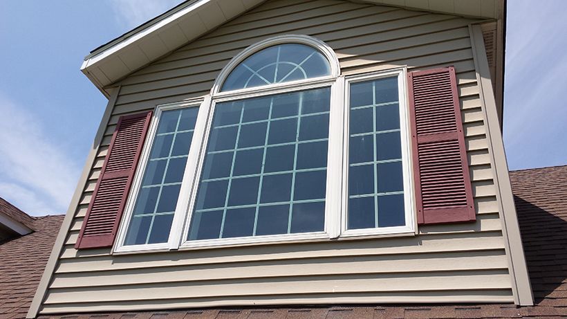 A large window on the side of a house with red shutters