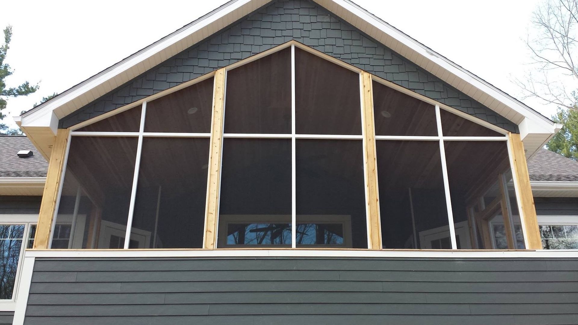 Screened porch with white frames, wood trim, and a dark blue exterior.